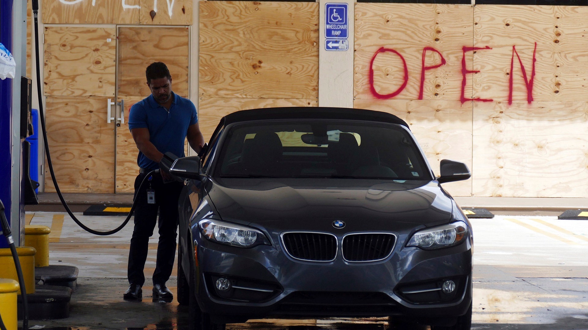 A man fills his car up at a gas station in Miami as the windows of the station were boarded up on Wednesday