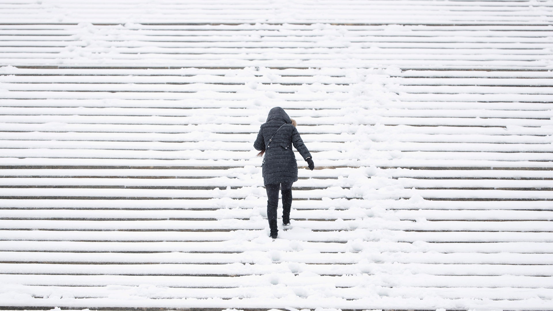 A woman climbs the snow covered steps of the Philadelphia Museum of Art during a winter storm.