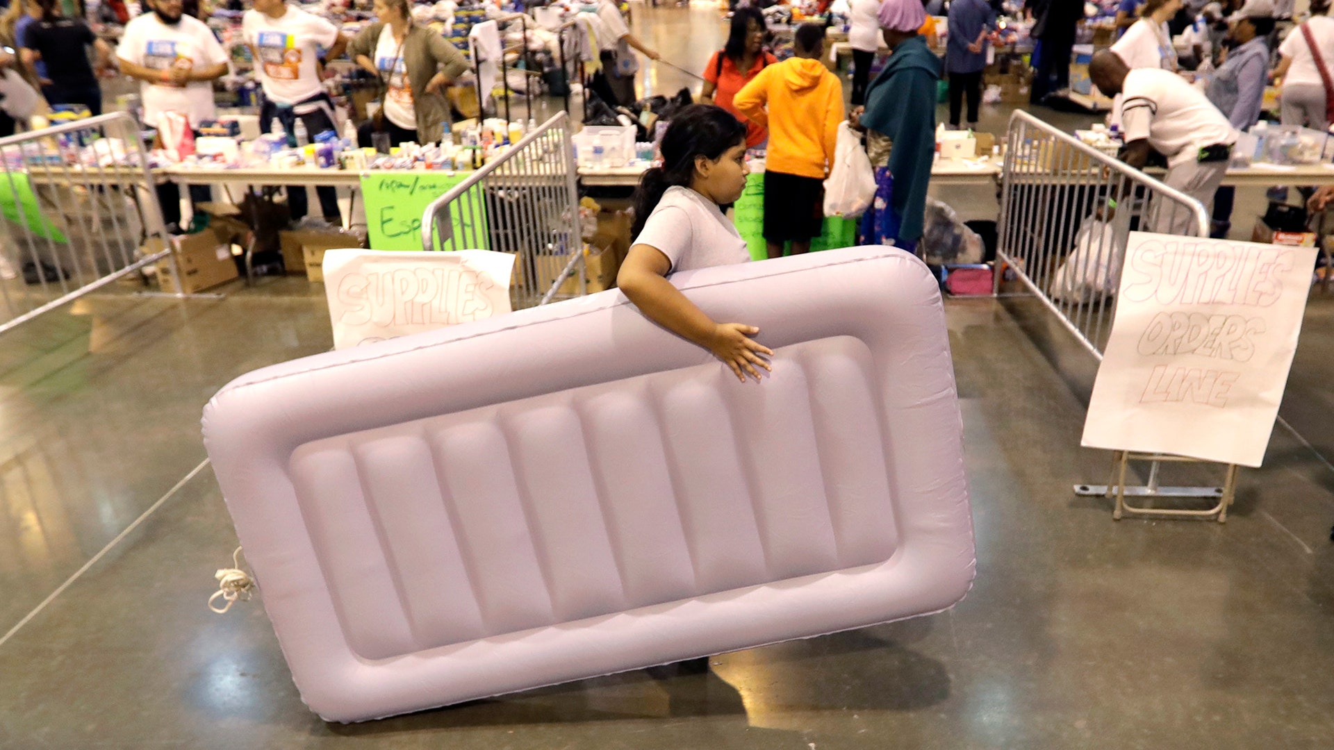 A girl carries an air mattress at a shelter setup inside NRG Center for flood victims of Harvey Wednesday, in Houston