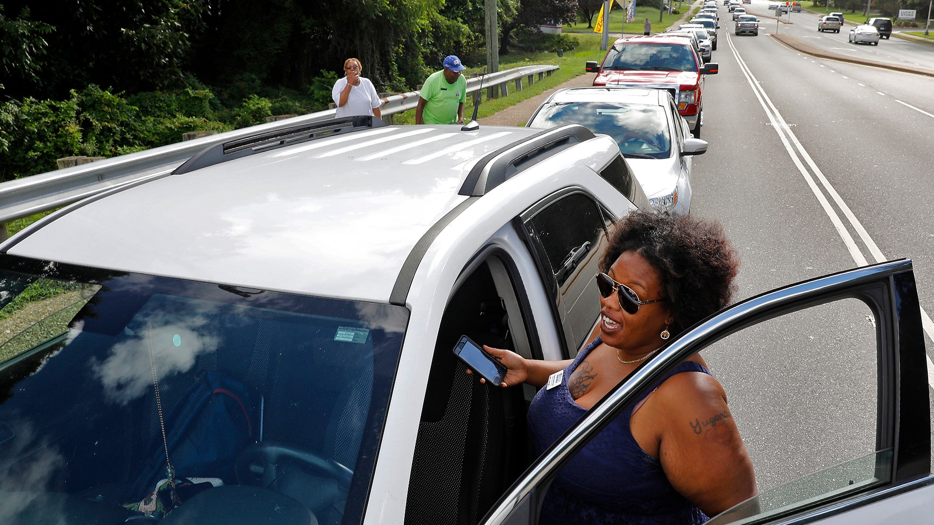 Yugonda Sample waits outside of her car as traffic backs up in Newport News, Virginia as people attempt to pickup sandbags, Wednesday