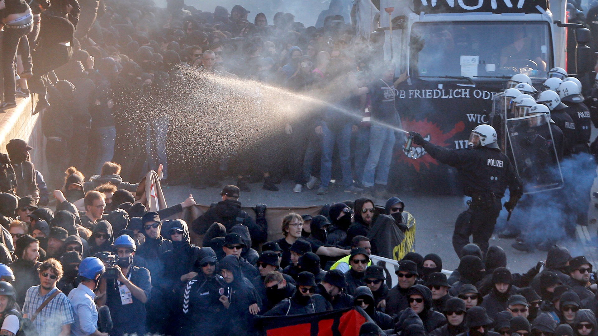 A police officer sprays protesters at the G-20 summit in Hamburg, Germany, Thursday, July 6, 2017