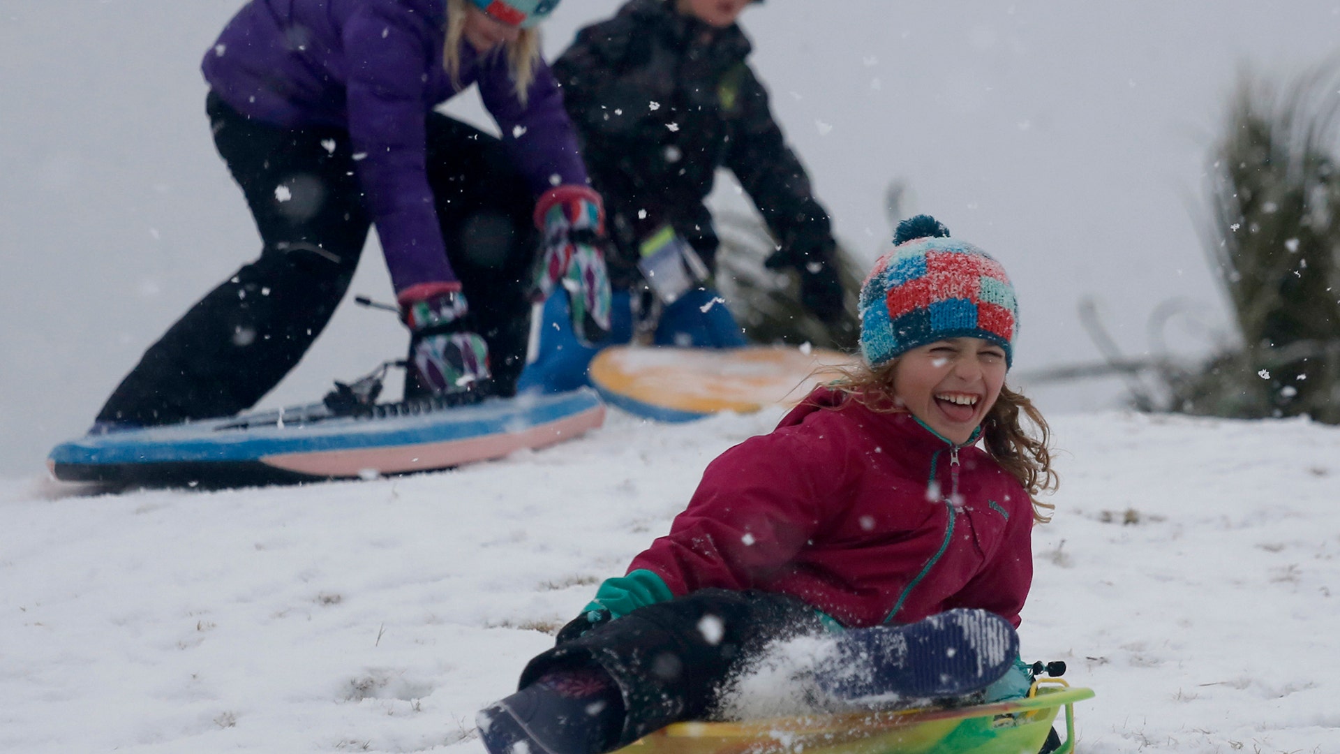 Children sled down a hill on a golf course at the Isle of Palms, S.C