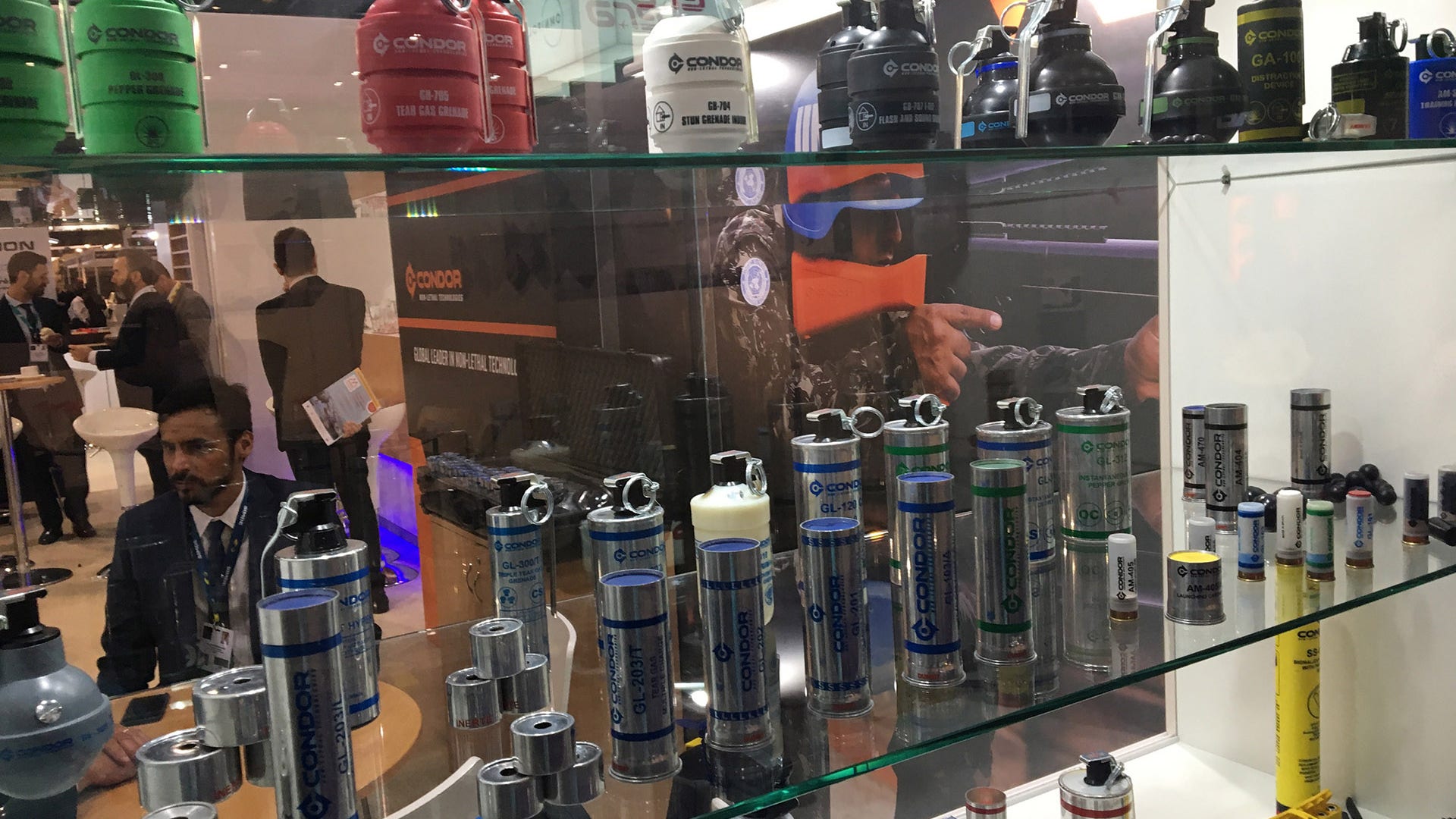 A man has a conversation in front of different artillery canisters.