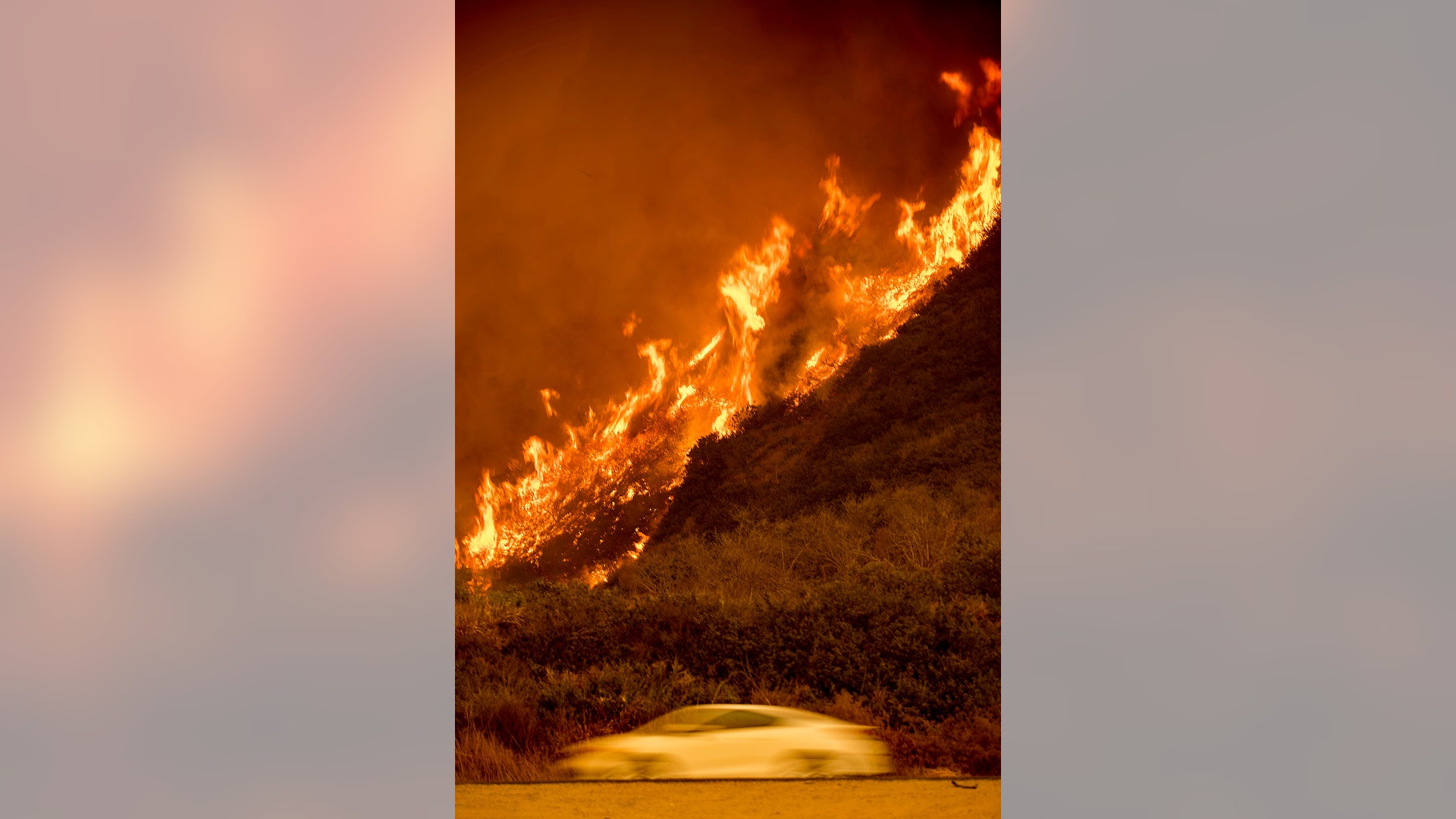 Flames from the Thomas fire burn above traffic on Highway 101 north of Ventura, California, Wednesday