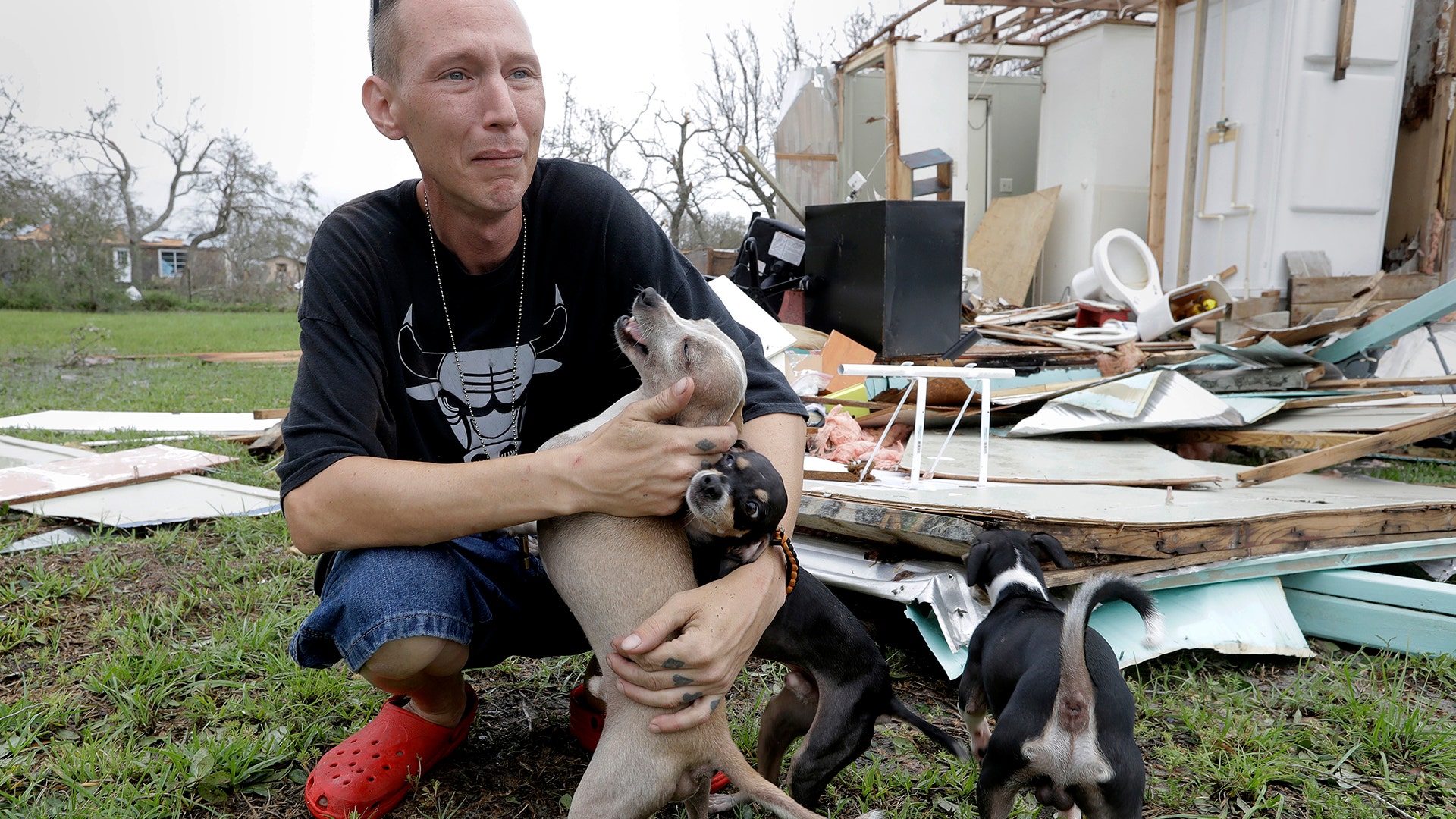 Sam Speights holds his dogs next to his damaged home in the wake of Hurricane Harvey in Rockport, Texas, Sunday