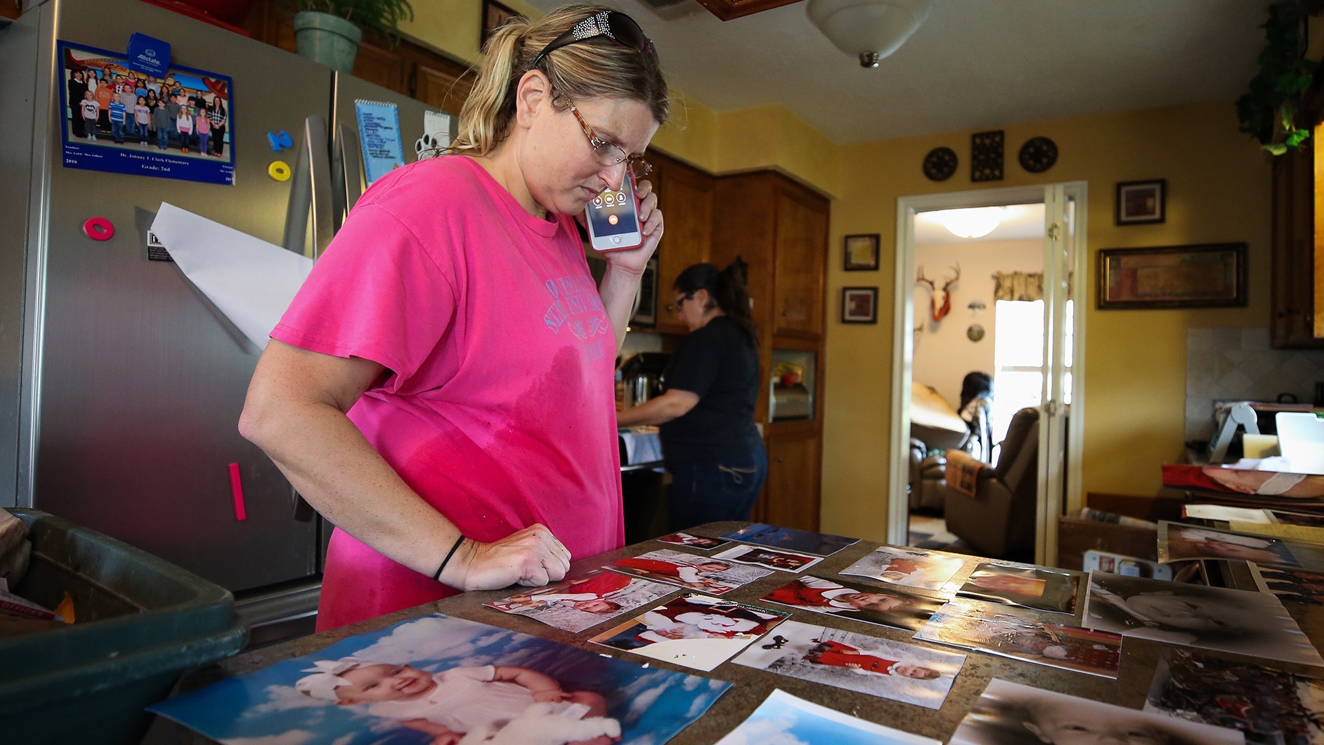 Laura Gill looks at family photos drying from their home that was flooded during Tropical Storm Harvey, Wednesday, in Baytown, Texas