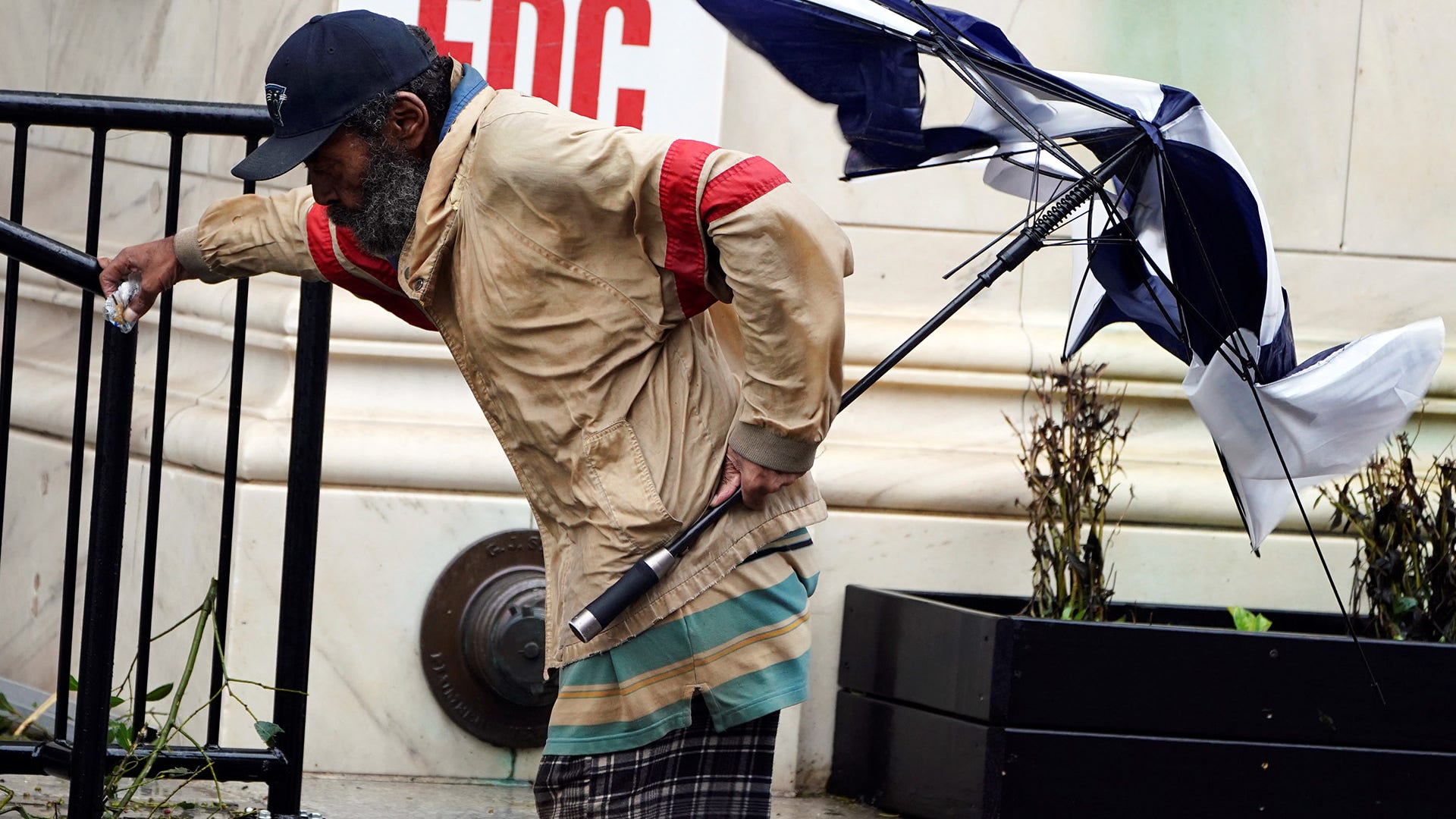 A man holds on to a rail as a gust of wind hits after Hurricane Florence struck on Wilmington, North Carolina, Saturday