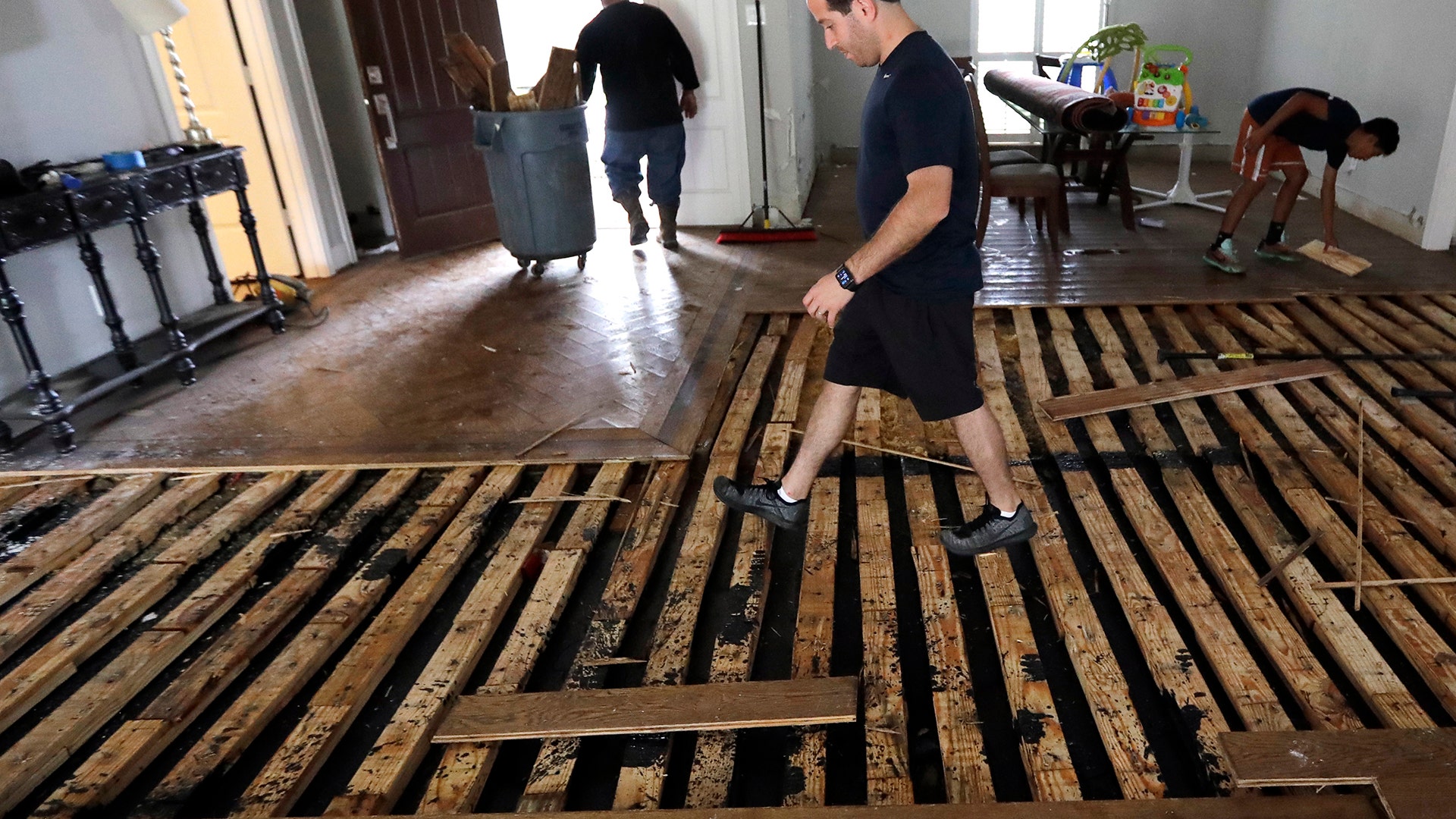 Michael Saghian walks across the living room of his home damaged by floodwaters in Houston, Wednesday