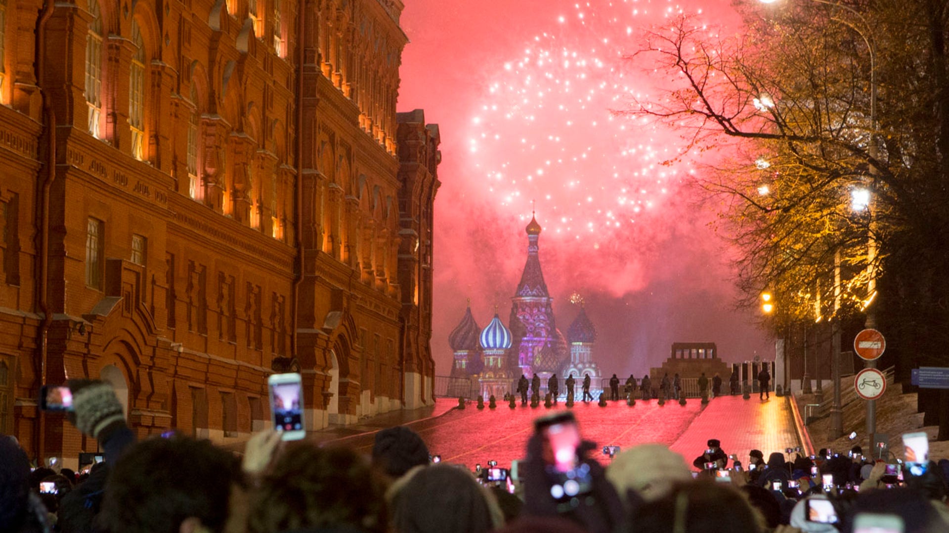 People watch as fireworks explode over the Kremlin standing at Red Square blocked by police during New Year celebrations in Moscow, Russia, Sunday, Jan. 1, 2017. 