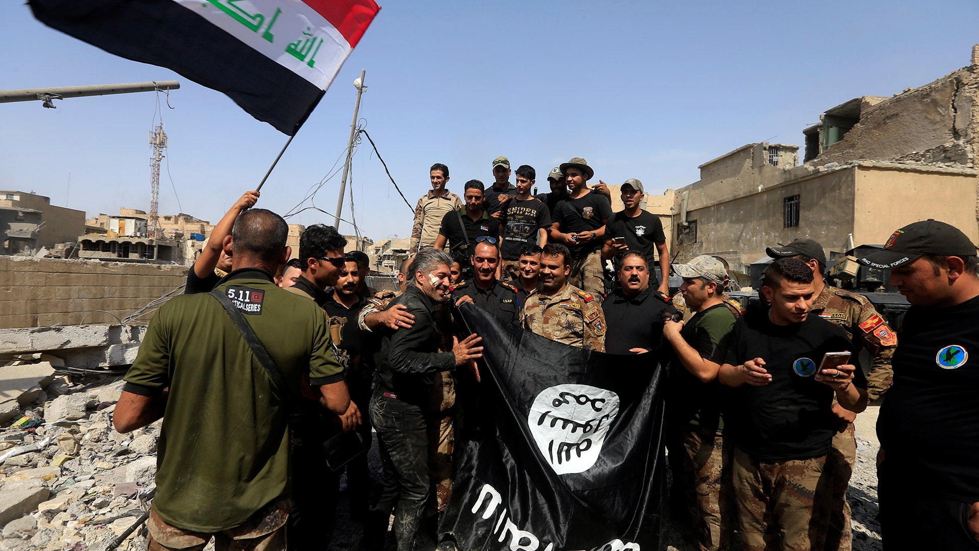 Iraqi Counter Terrorism Service hold an Islamic State flag, which they pulled down in the Old City of Mosul, Iraq, July 9, 2017