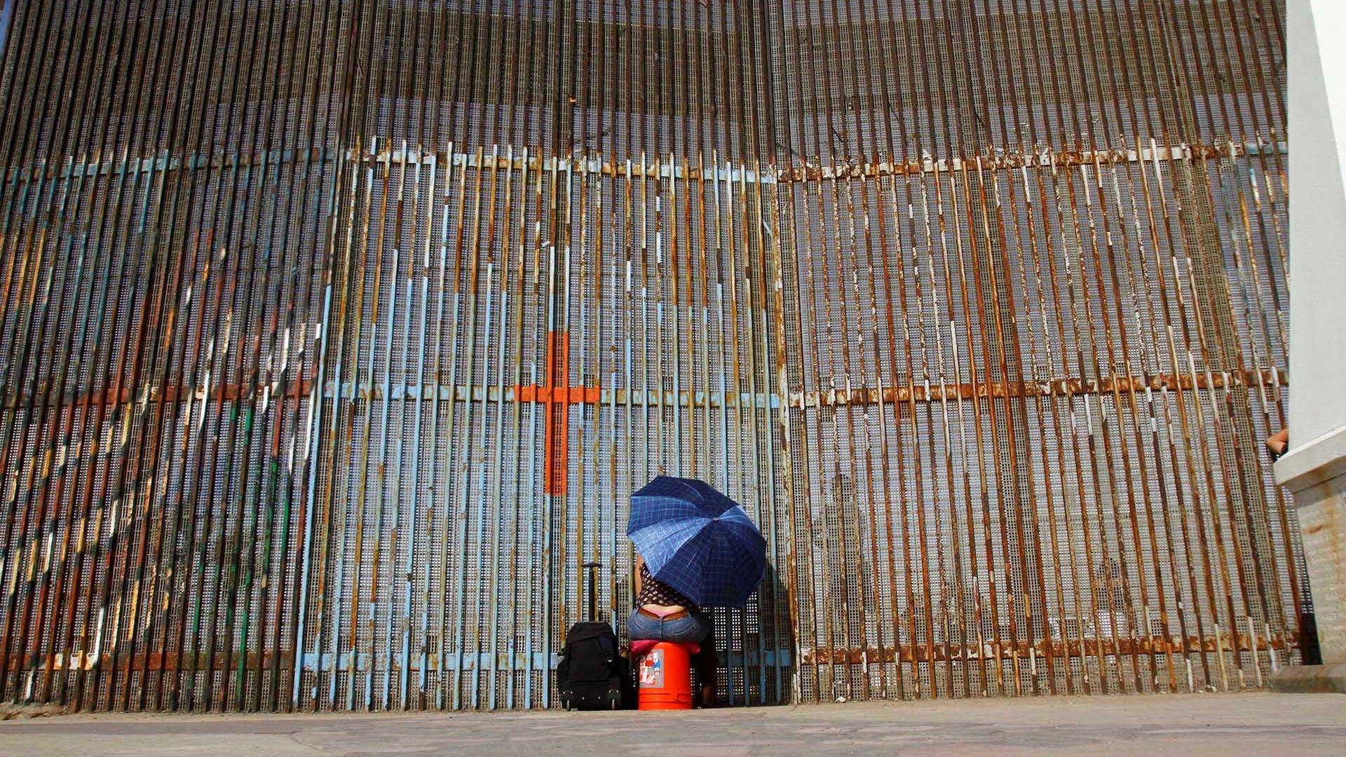 A woman talks to her relatives across a fence separating Mexico and the United States, in Tijuana, Mexico.