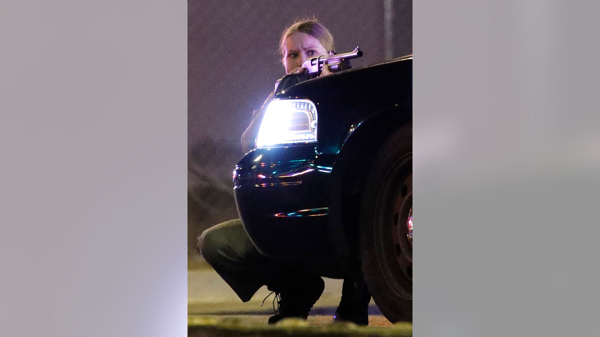 A police officer takes cover behind a police vehicle during a shooting near the Mandalay Bay resort and casino on the Las Vegas Strip, Sunday