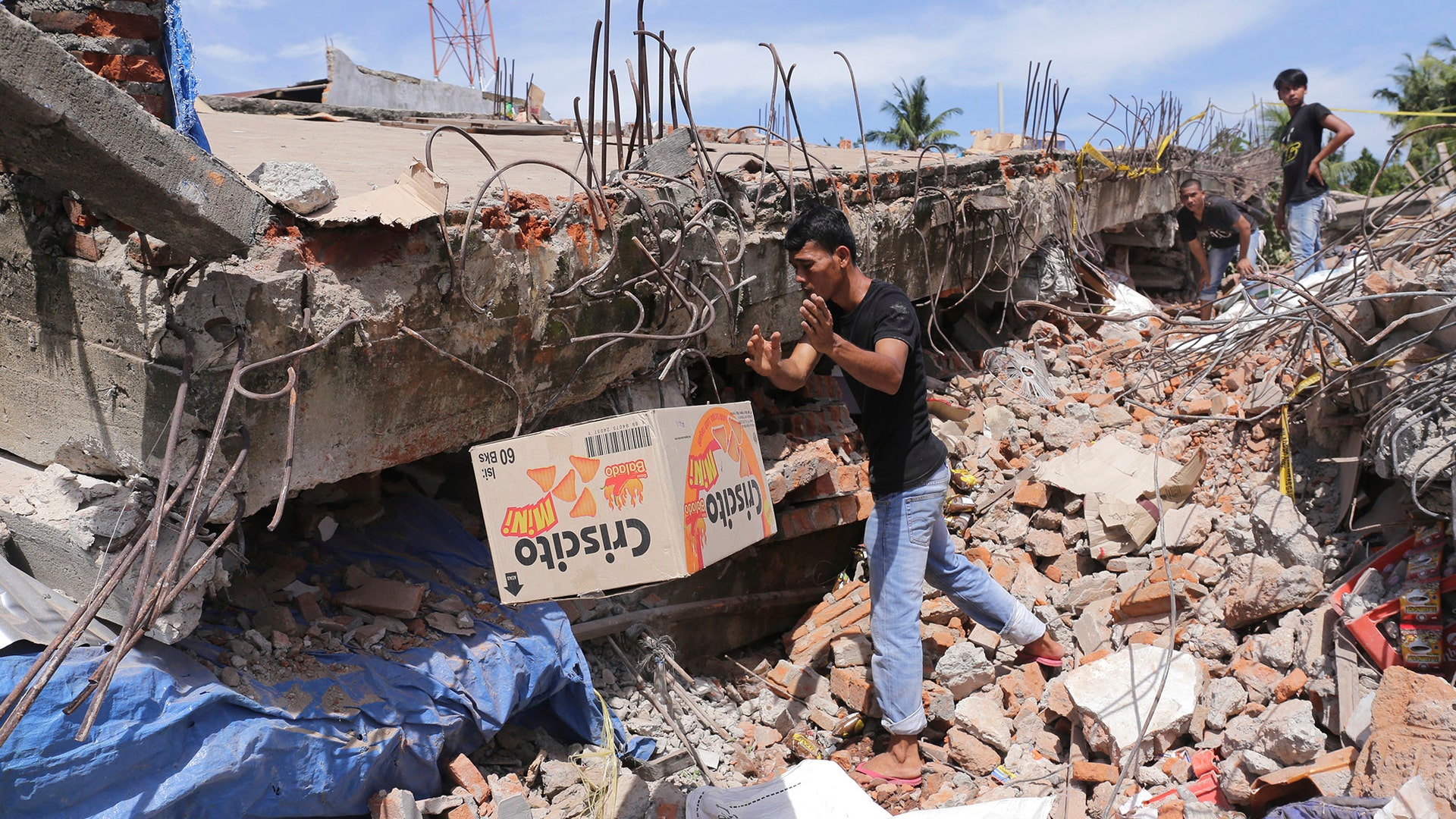 A man removes a box of food from under the rubble of a building that collapsed after an earthquake in Pidie Jaya, Aceh province, Indonesia,.