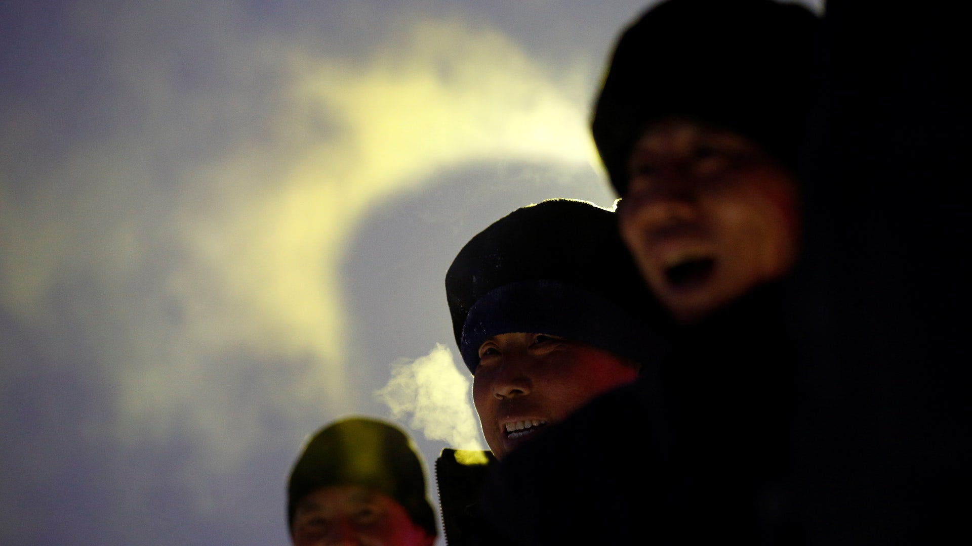Workers smile under an ice sculpture.
