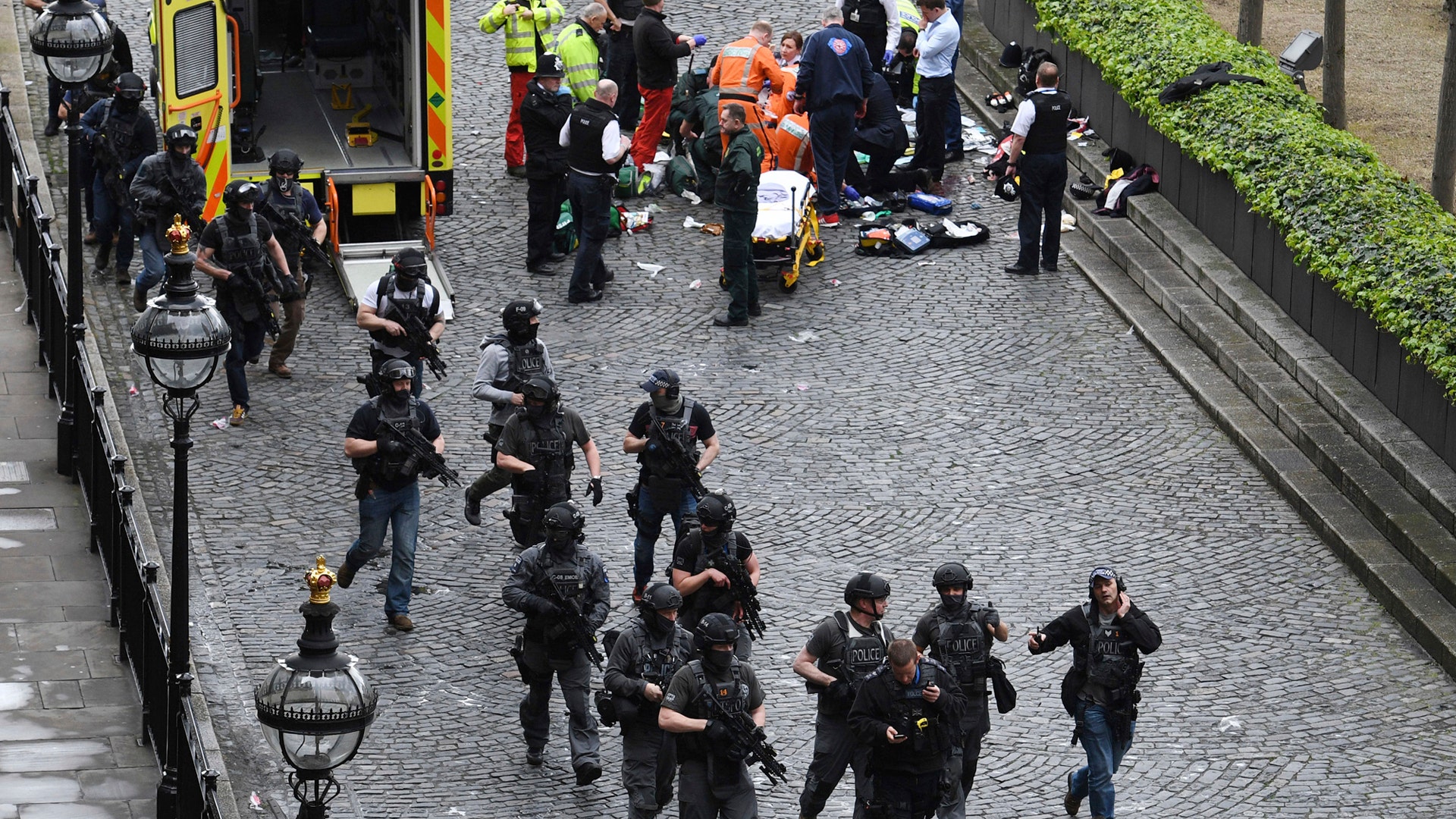 Armed police walk past emergency services attending to injured people on the floor outside the Parliament.