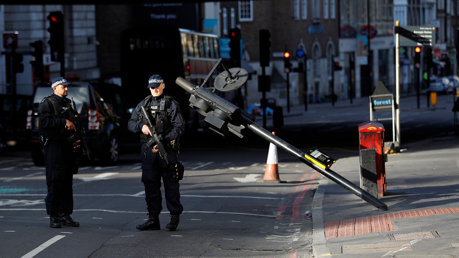 Armed police officers stand near the site where attackers crashed their van after running over pedestrians on London Bridge