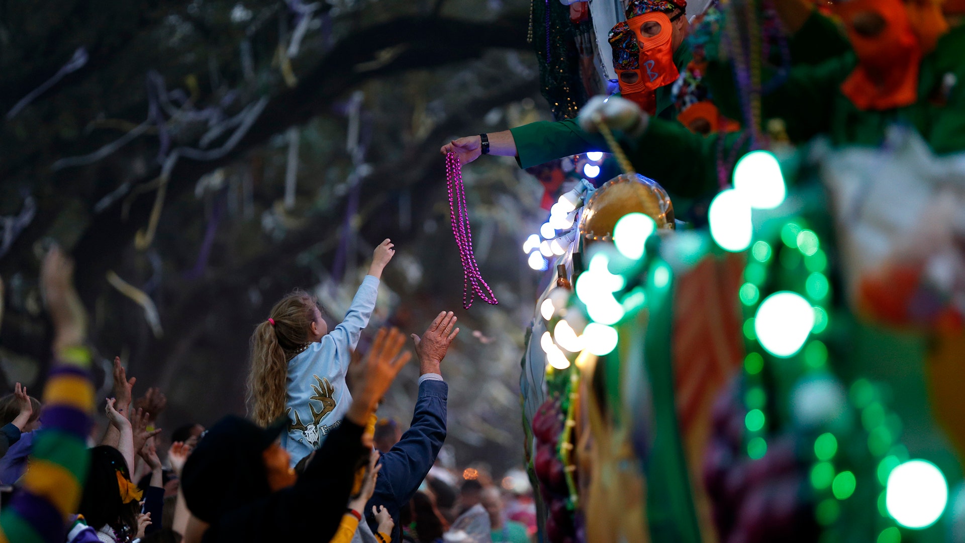  A float rider hands beads to a child during the Krewe of Bacchus Mardi Gras parade in New Orleans.