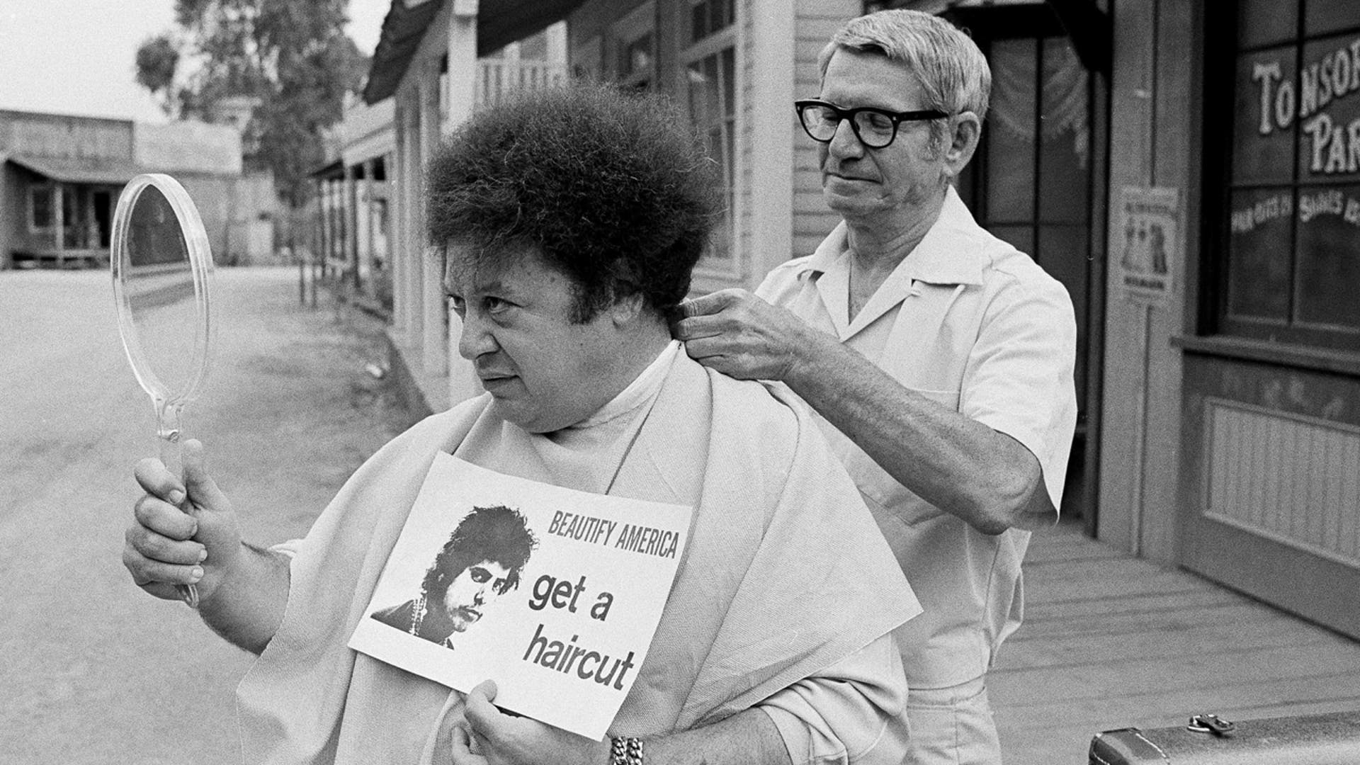 FILE - In this Aug. 15, 1968, file photo, comedian Marty Allen, fuzzy-haired member of the comedy team of Allen & Rossi, has his hair styled by barber Sol Goldstein in Hollywood, Calif. Allen's spokeswoman Candi Cazau says he died Monday, Feb. 12, 2018, of complications from pneumonia. His wife and performing partner Karon Kate Blackwell was by his side. He was 95. (AP Photo/Wally Fong, File)