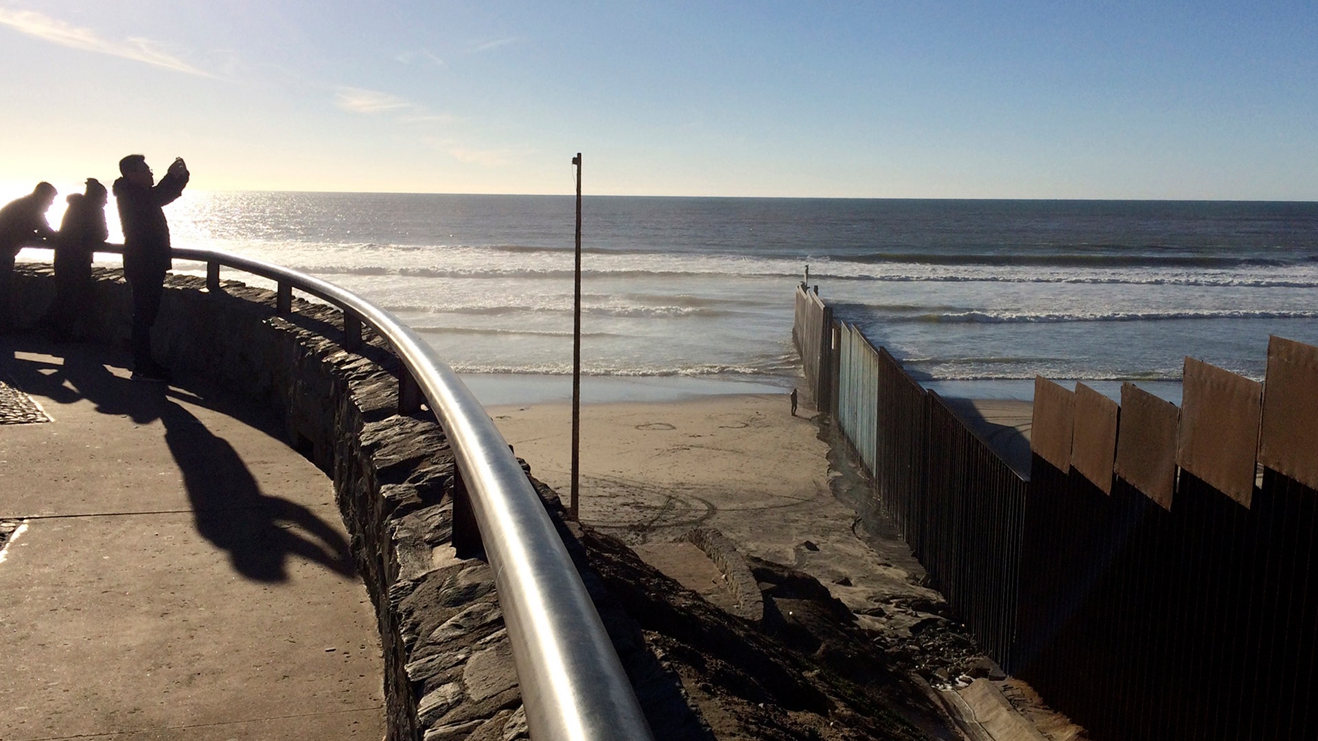 People look out to where a border structure separates San Diego, right, from Tijuana, Mexico, left.