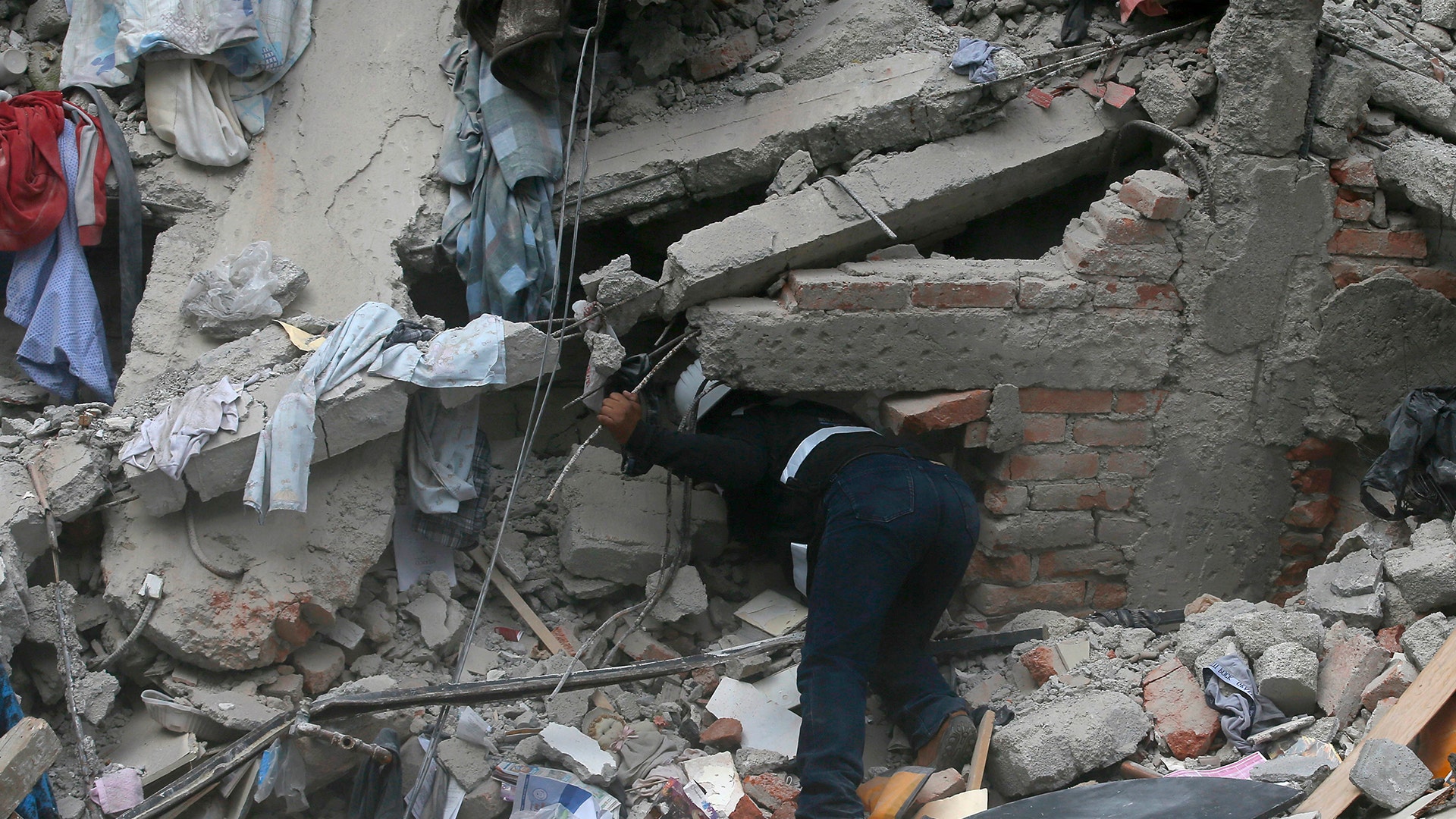 A construction worker searches a building that collapsed