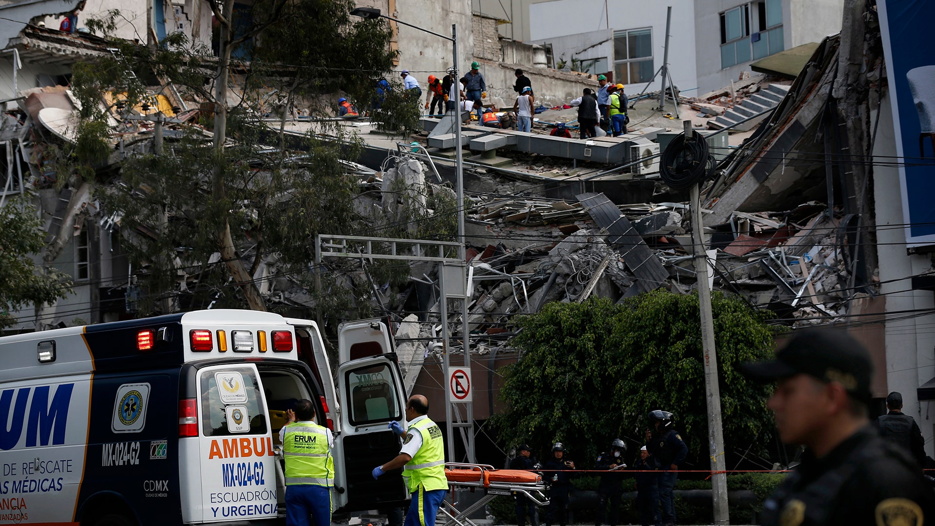 Rescue workers and volunteers search a building that collapsed 