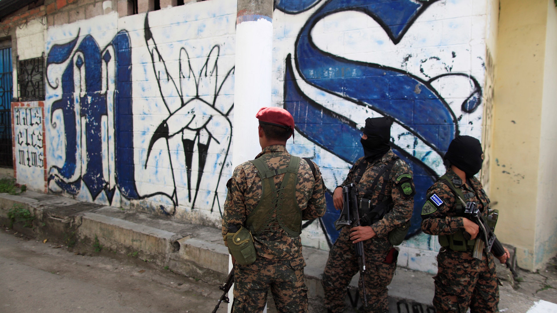 Soldiers stand guard close to a Mara Salvatrucha gang related graffiti in Soyapango, El Salvador