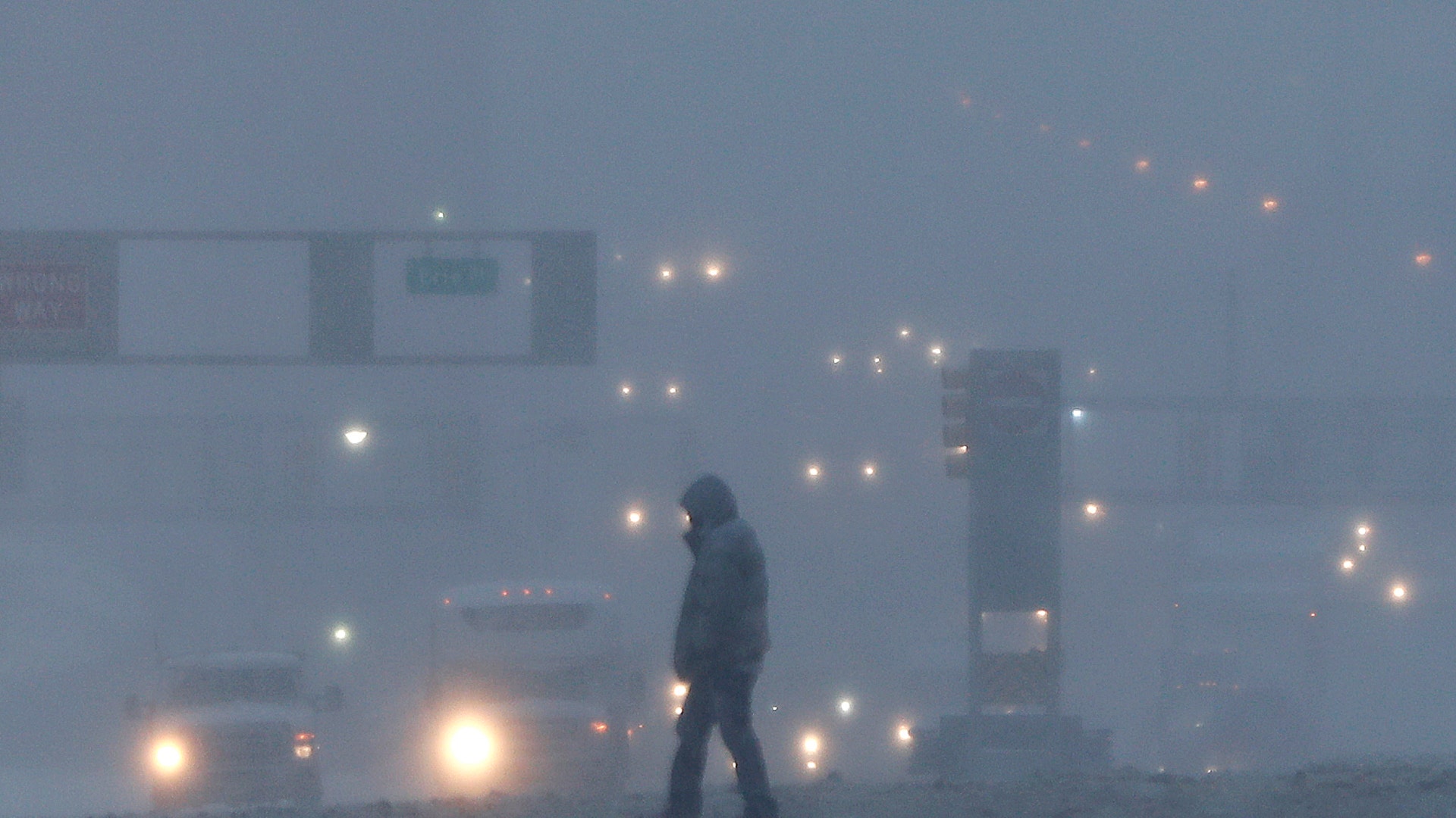 A pedestrian crosses a snow-covered intersection as snow falls, Thursday, Feb. 9, 2017, in Jersey City, N.J. 