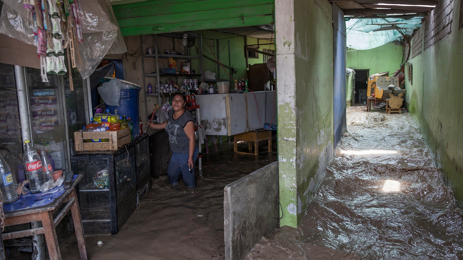 A woman works to salvage belongings from her flooded home in Lima, Peru.