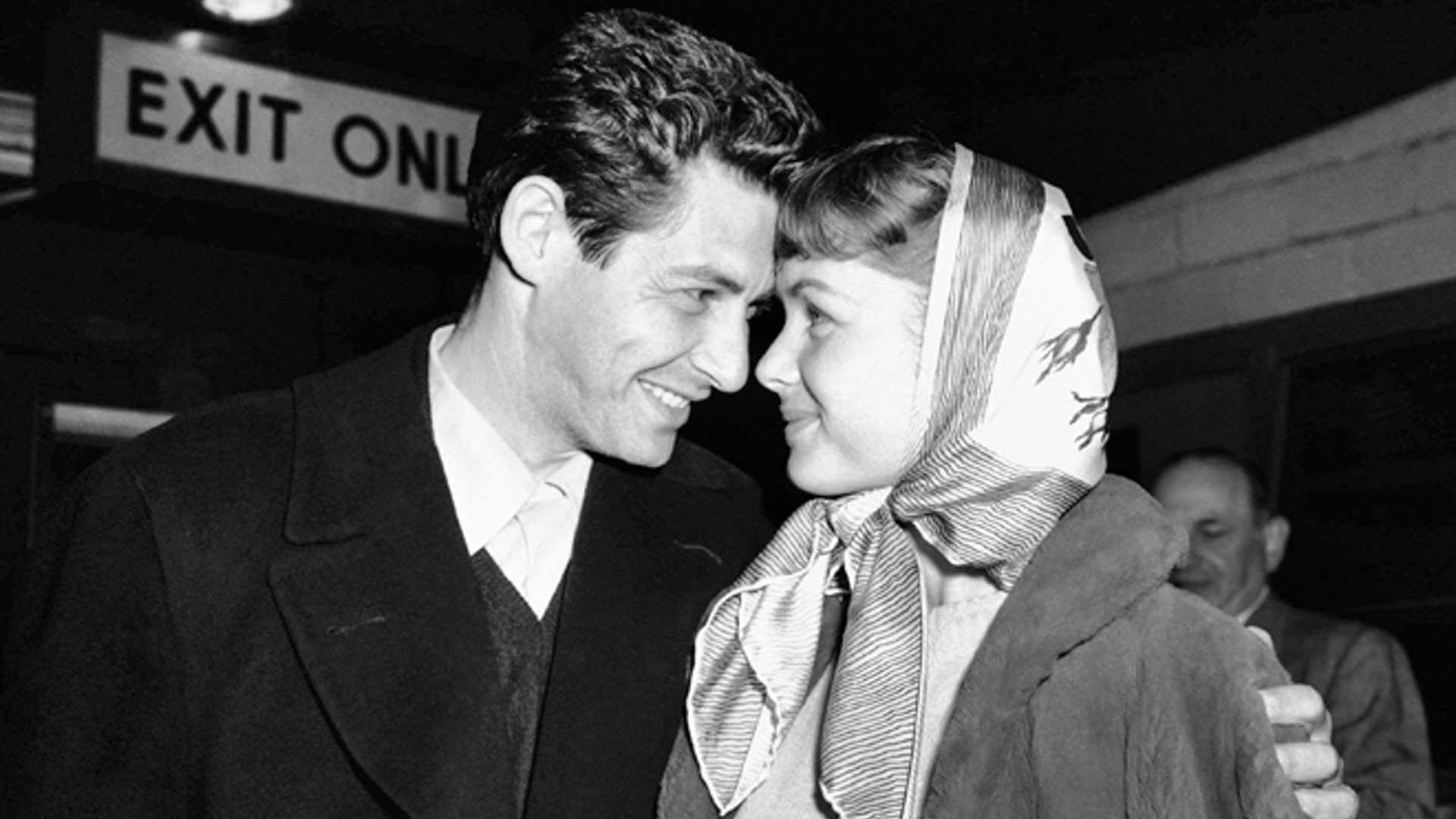 April 19, 1955: Singer Eddie Fisher and his fiancee, actress Debbie Reynolds, look at each other at Idlewild Airport in New York.