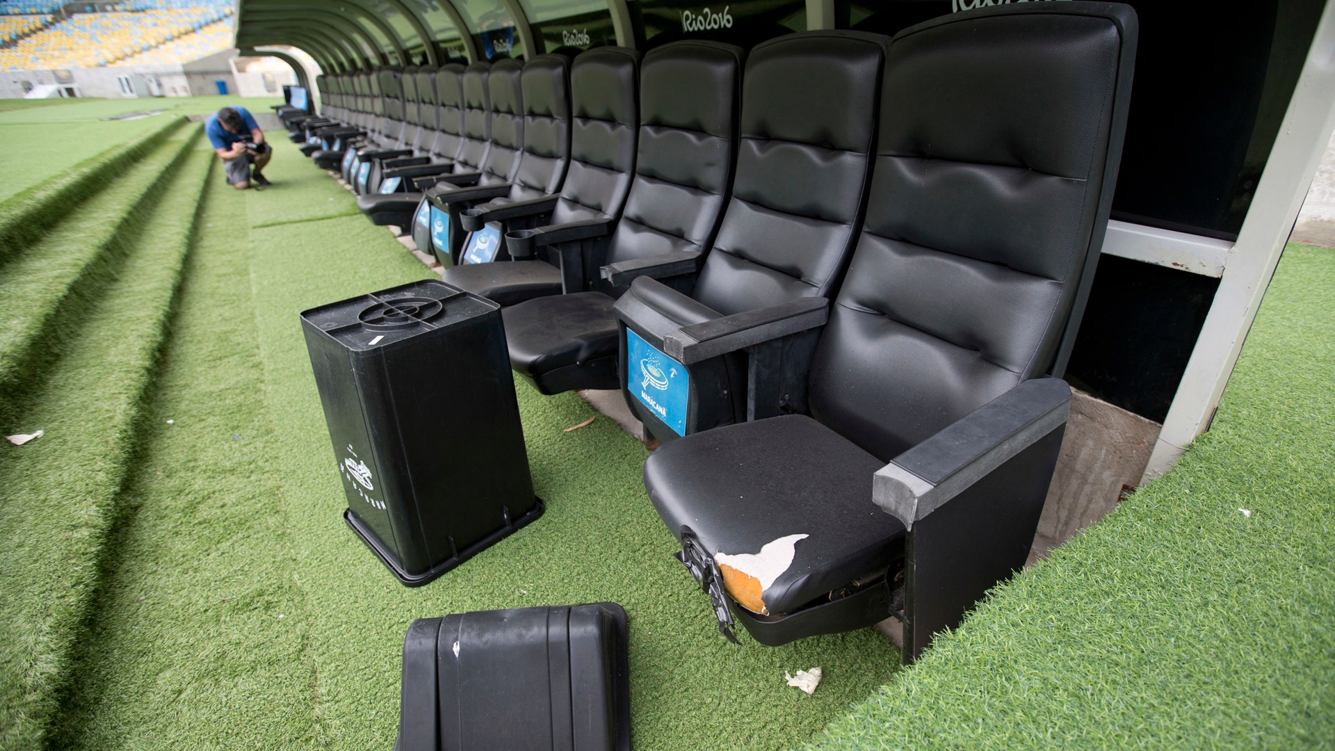 A trash can lays by ripped seats at one of the dugouts in Maracana stadium. 