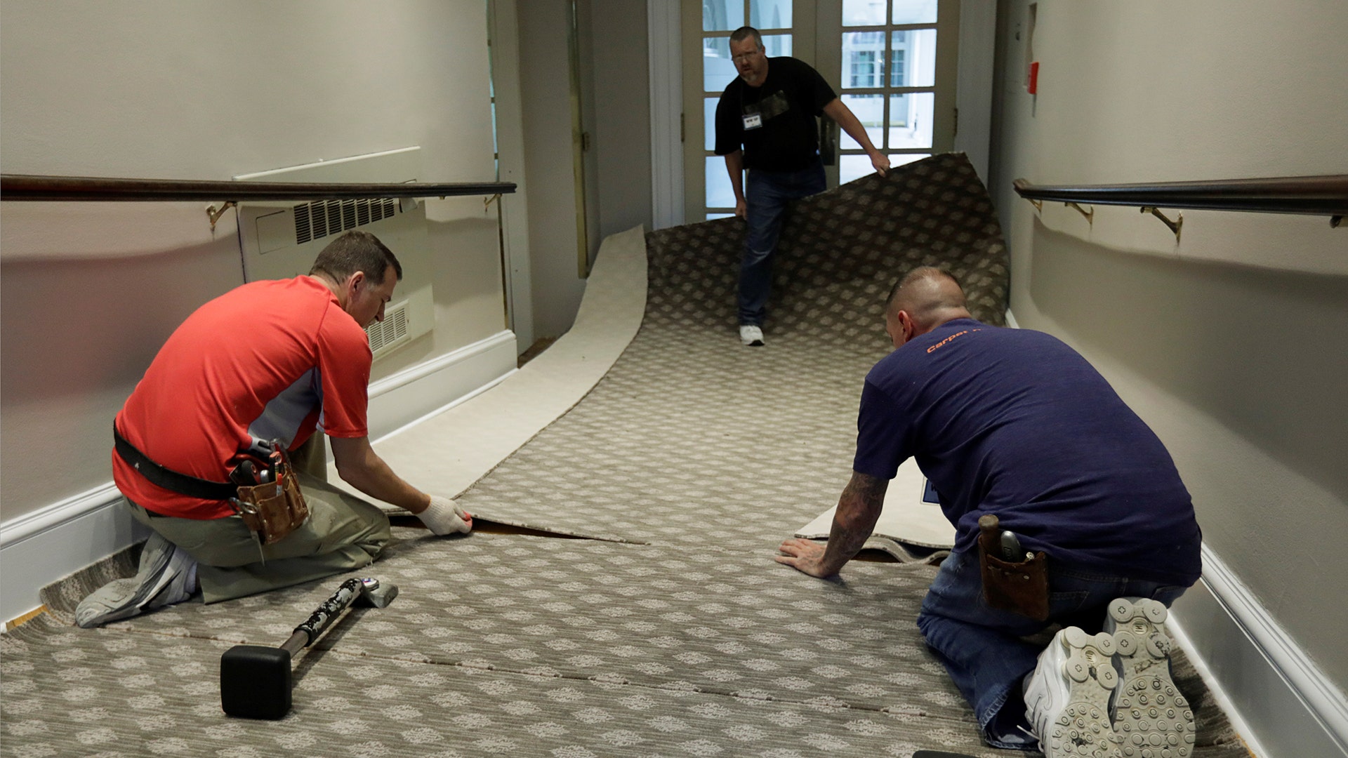 Construction workers lay carpet on a ramp from the West Wing offices to the White House colonnade during renovations 