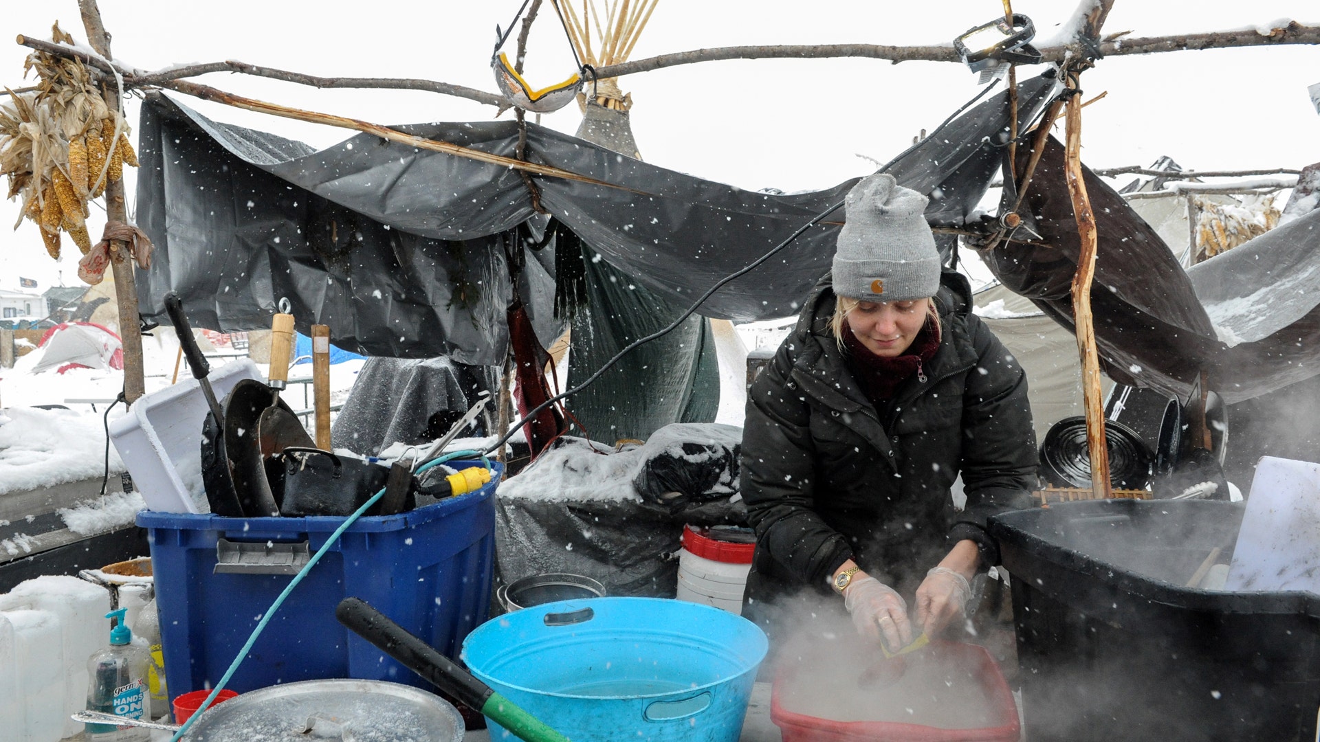 A woman washes dishes in the Oceti Sakowin camp in a snow storm during a protest against plans to pass the Dakota Access pipeline.
