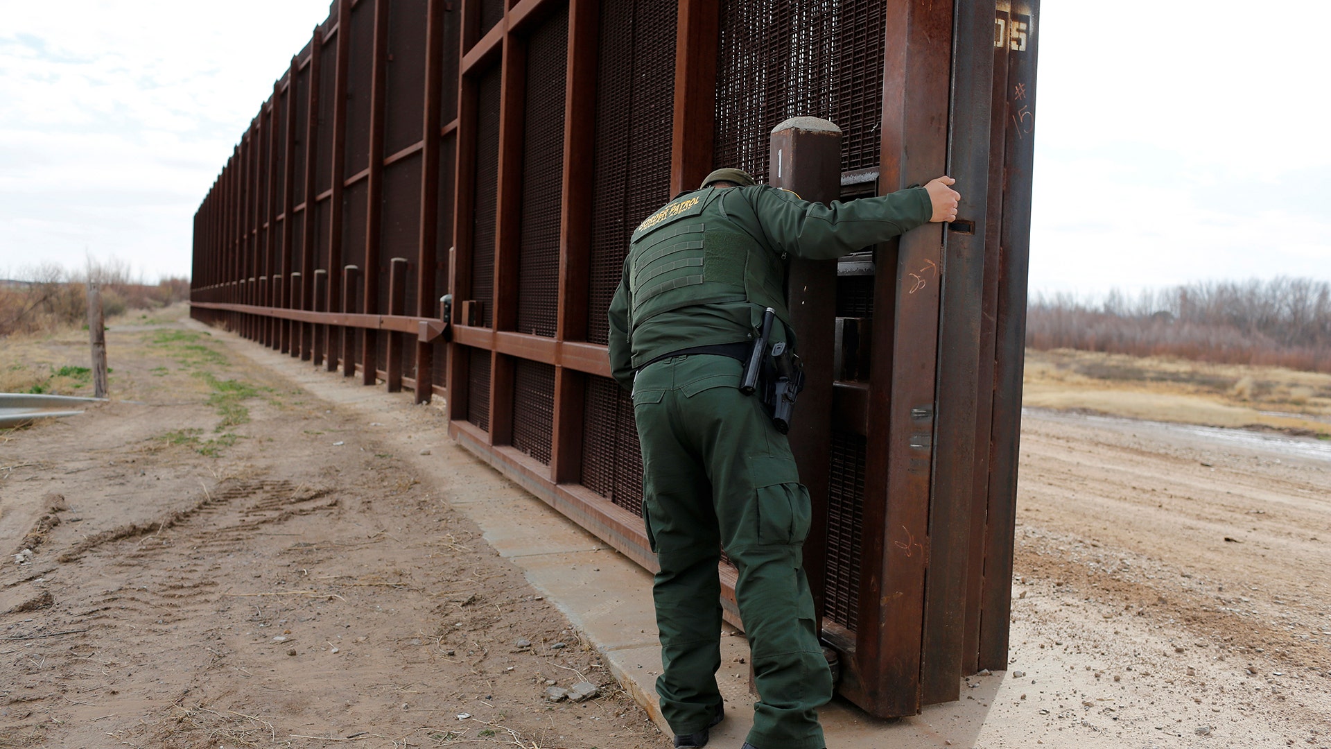 A U.S. Border patrol agent opens a gate on the fence along the Mexico border to allow vehicles pass in El Paso.