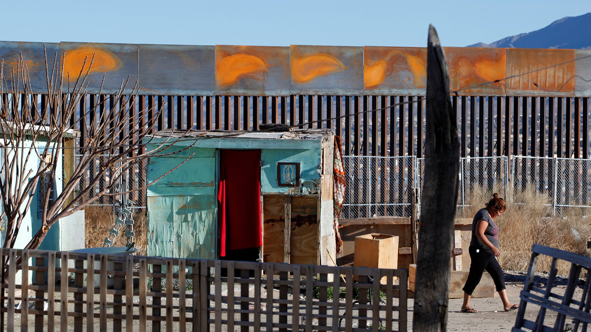 A woman is pictured at the patio of her house by a newly built section of the U.S.-Mexico border fence.