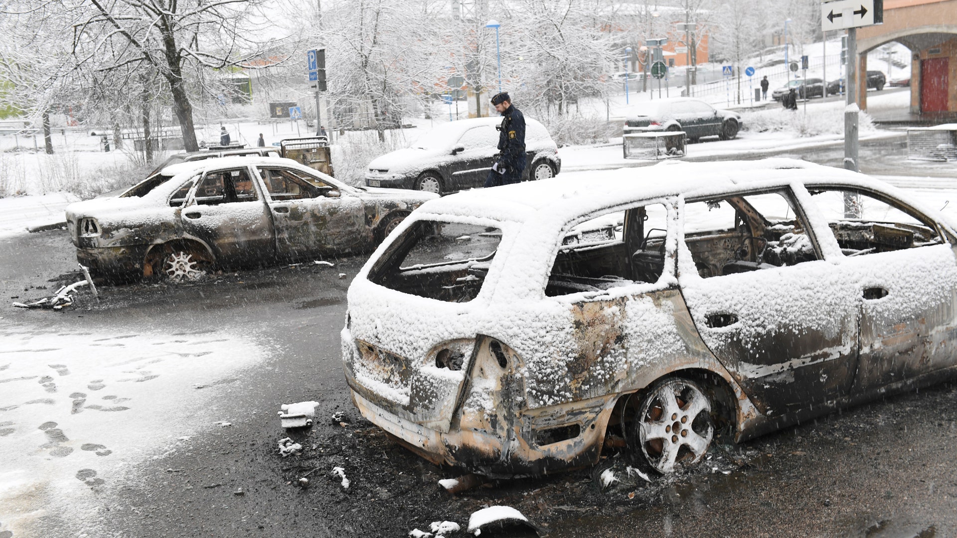 A policeman investigates a burnt car in Rinkeby, February 21, 2017. 