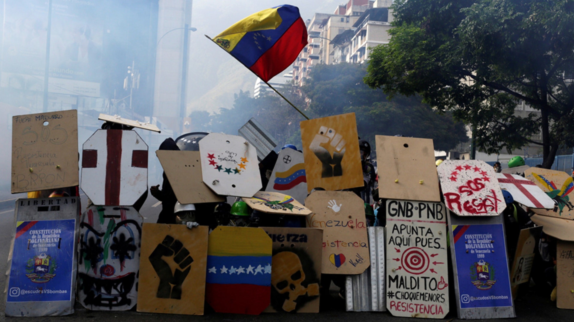 Opposition supporters use homemade shields to protect themselves while clashing with riot security forces in Venezuela