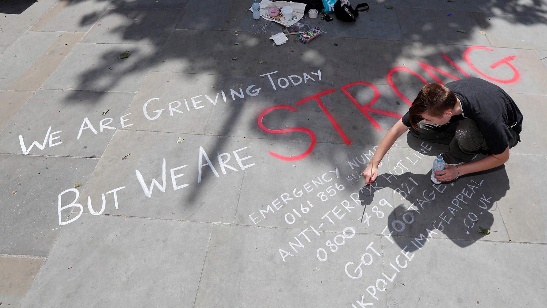 A man writes a message on the pavement in central Manchester, England