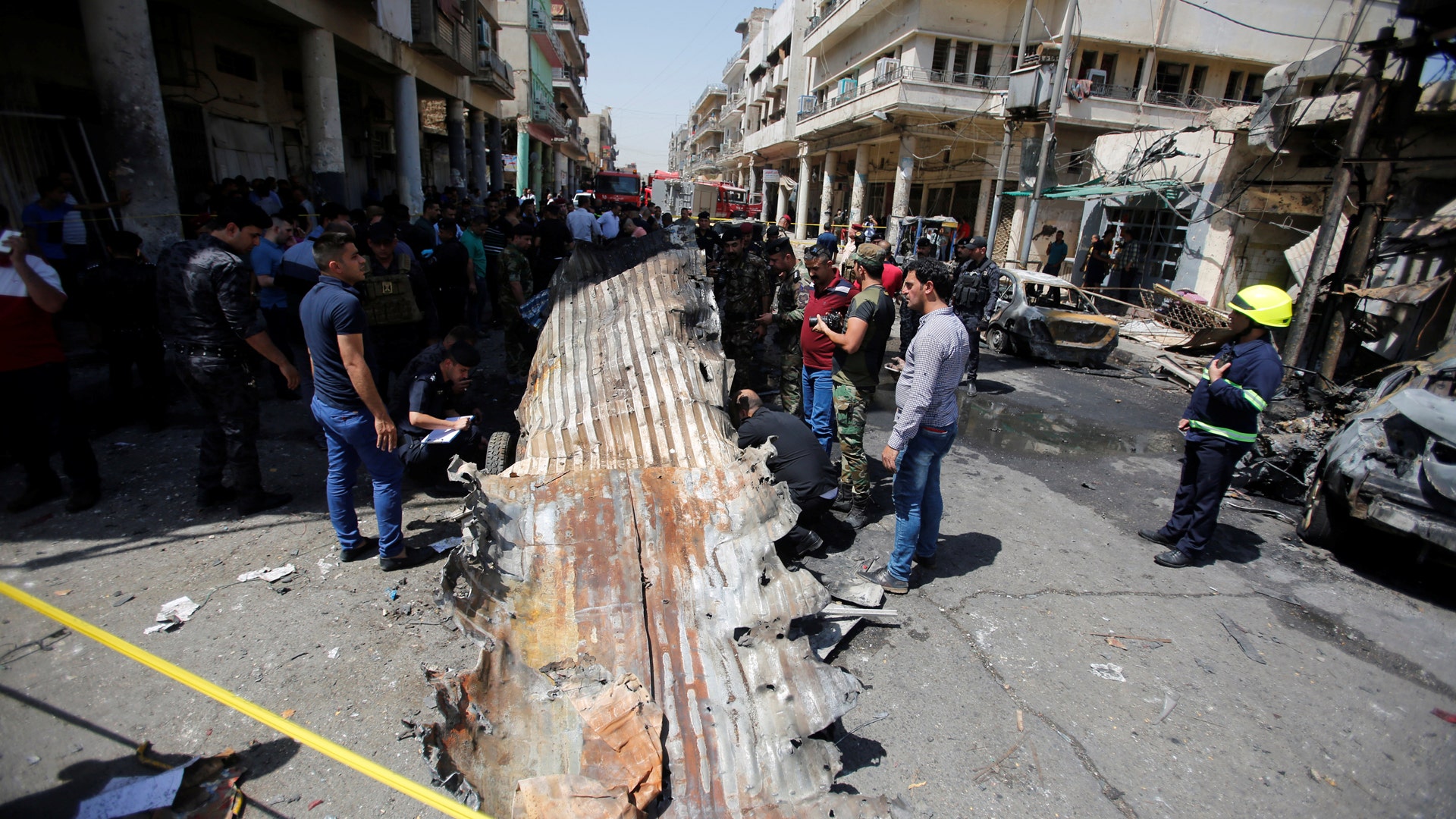 People gather at the site of car bomb attack near a government office in Karkh district in Baghdad