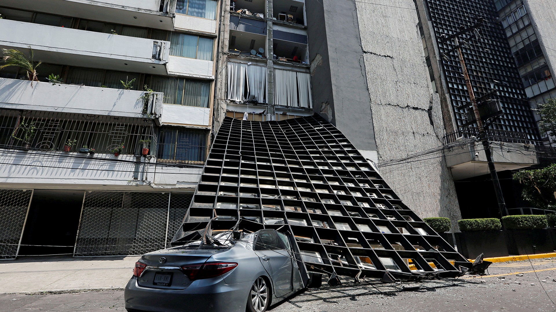 A damaged car is seen outside a building after an earthquake in Mexico City, Tuesday