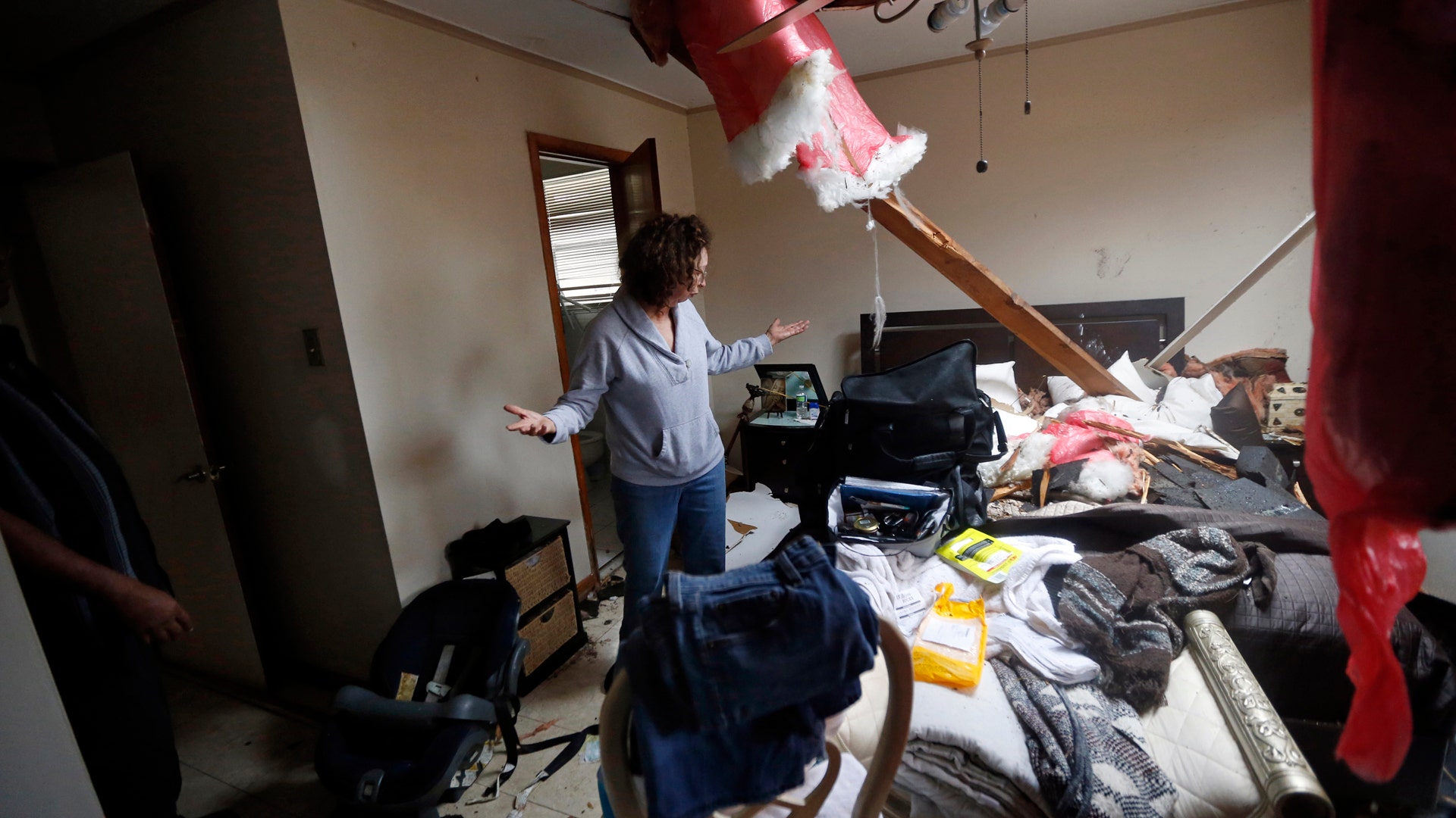 Artie Chaney reacts to her damaged home after a tornado struck while she and family members took cover inside.