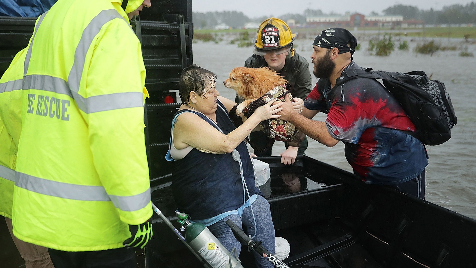 Rescue workers from Township 7 Fire Department help a woman and her dog in James City, North Carolina, Friday