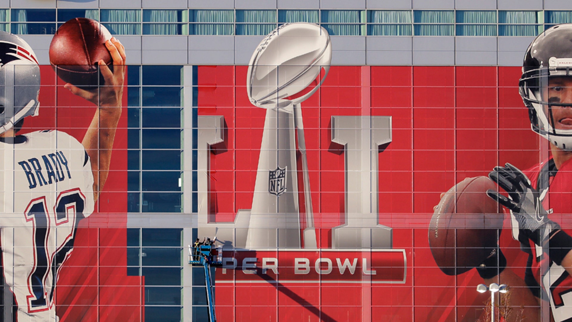 Workers attach a sign to the front of NRG Stadium in Houston, TX.