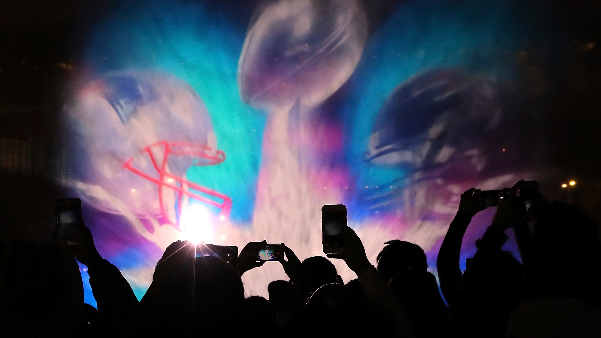Football fans snap photos of the 3D light show on water spray at Super Bowl Live in Discovery Green park.