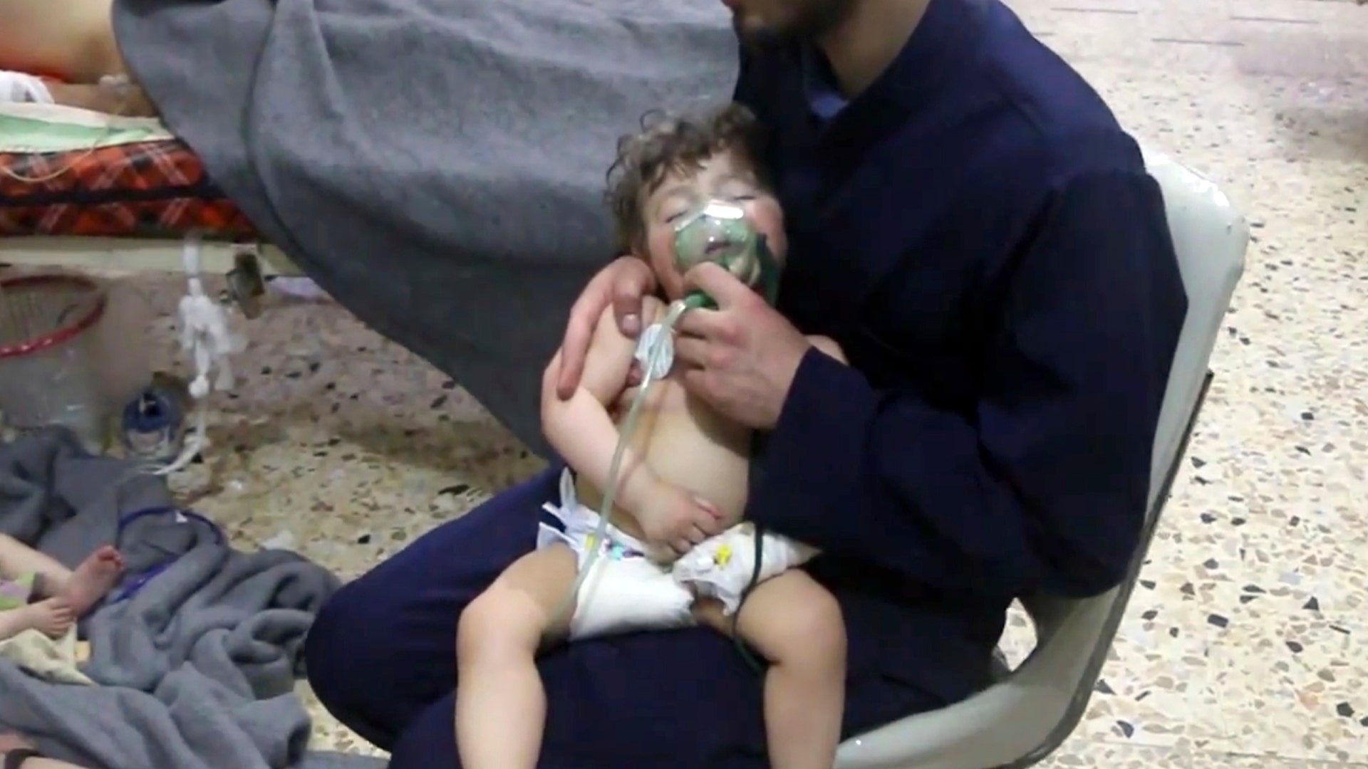 A medical worker giving toddlers oxygen through respirators following a poison gas attack in the opposition-held town of Douma.