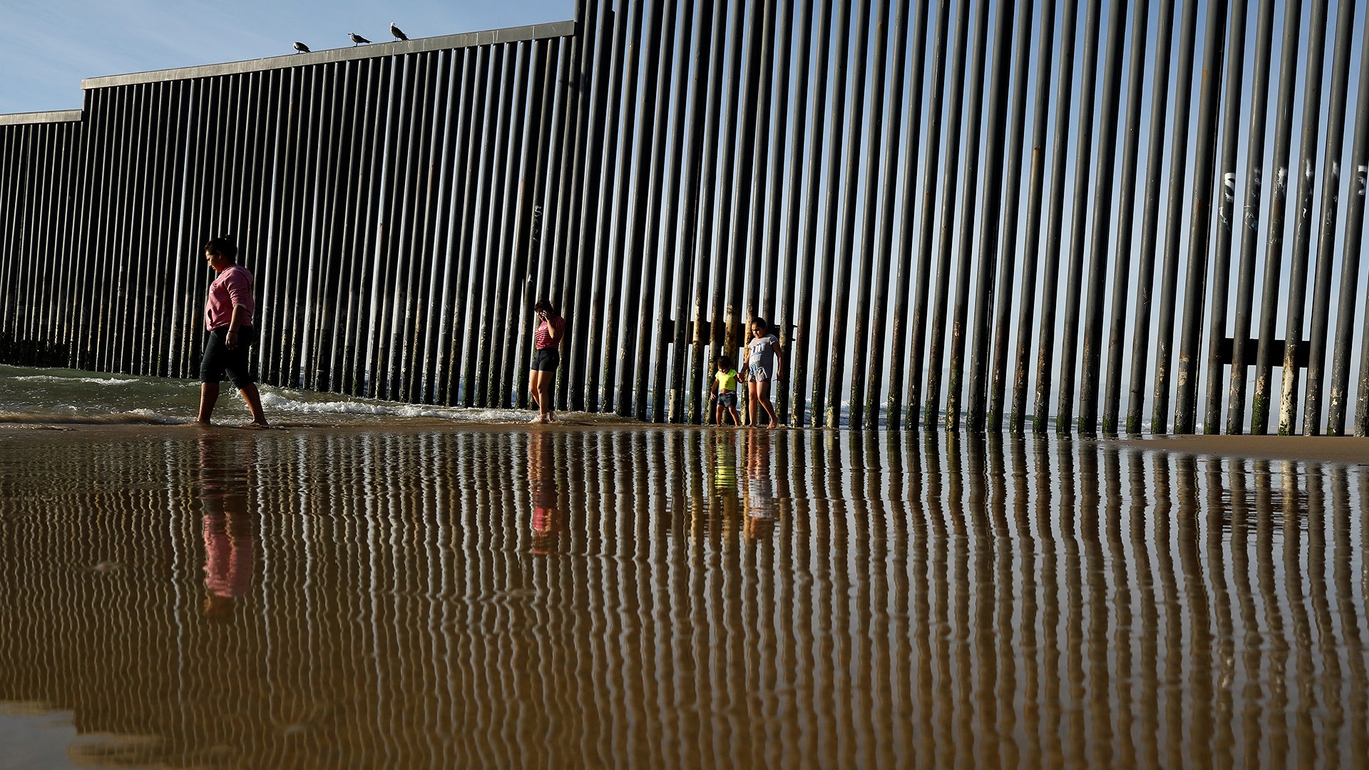 The border structure separating San Diego from Tijuana, Mexico, as people walk along the beach in Tijuana.