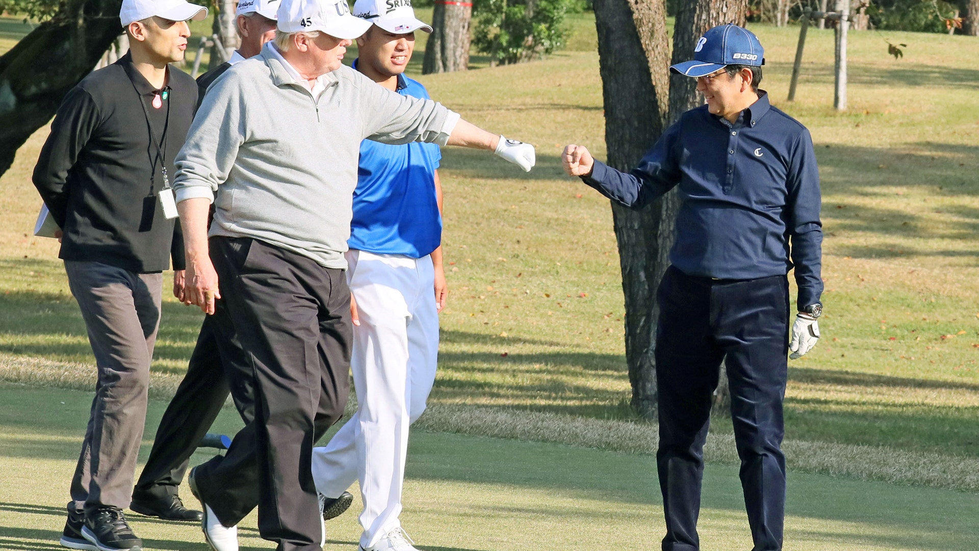 President Trump gestures to Japan's Prime Minister Shinzo Abe as Japanese professional golfer Hideki Matsuyama looks on.