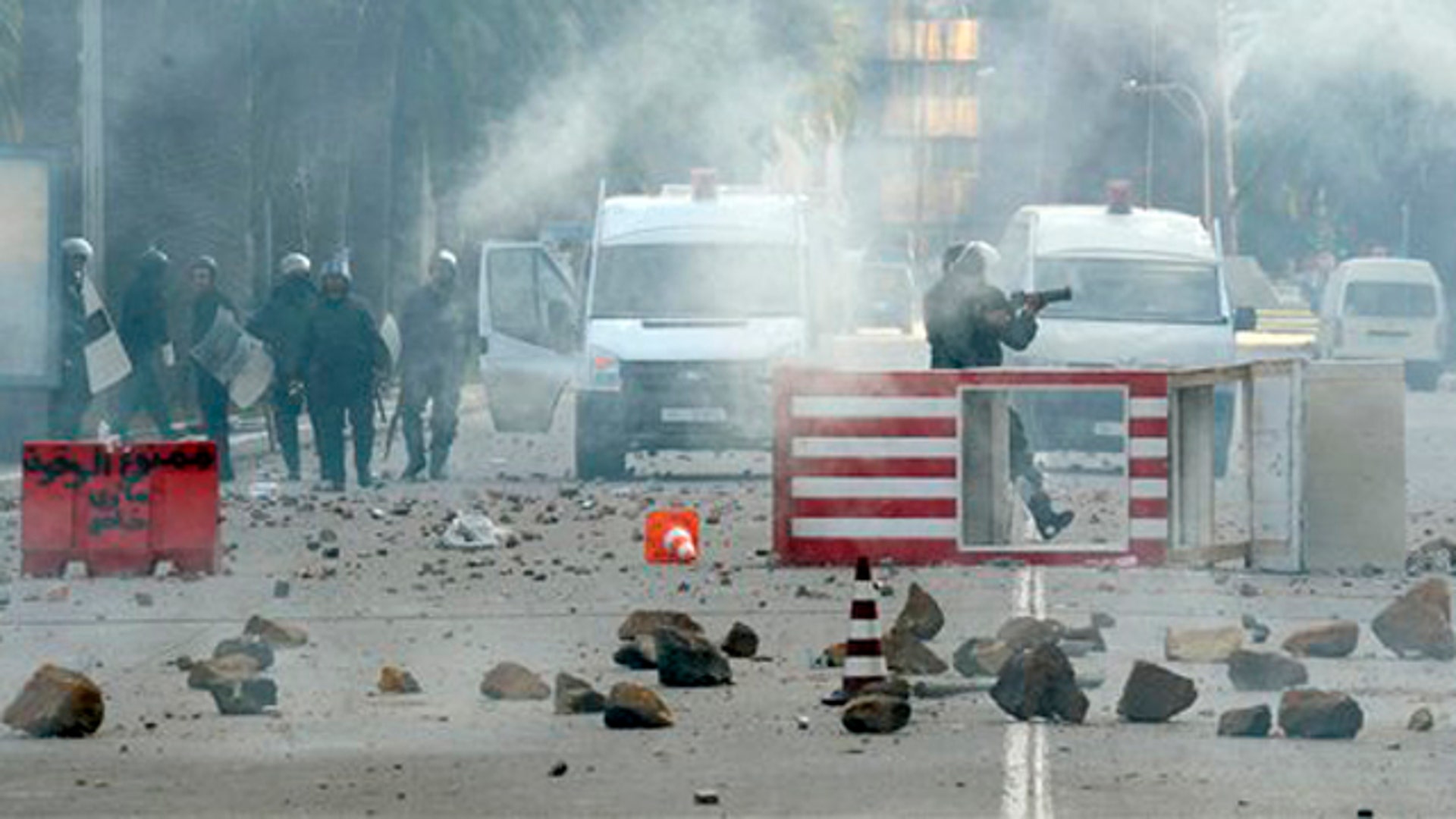 A Tunisian riot police officer fires a tear gas canister