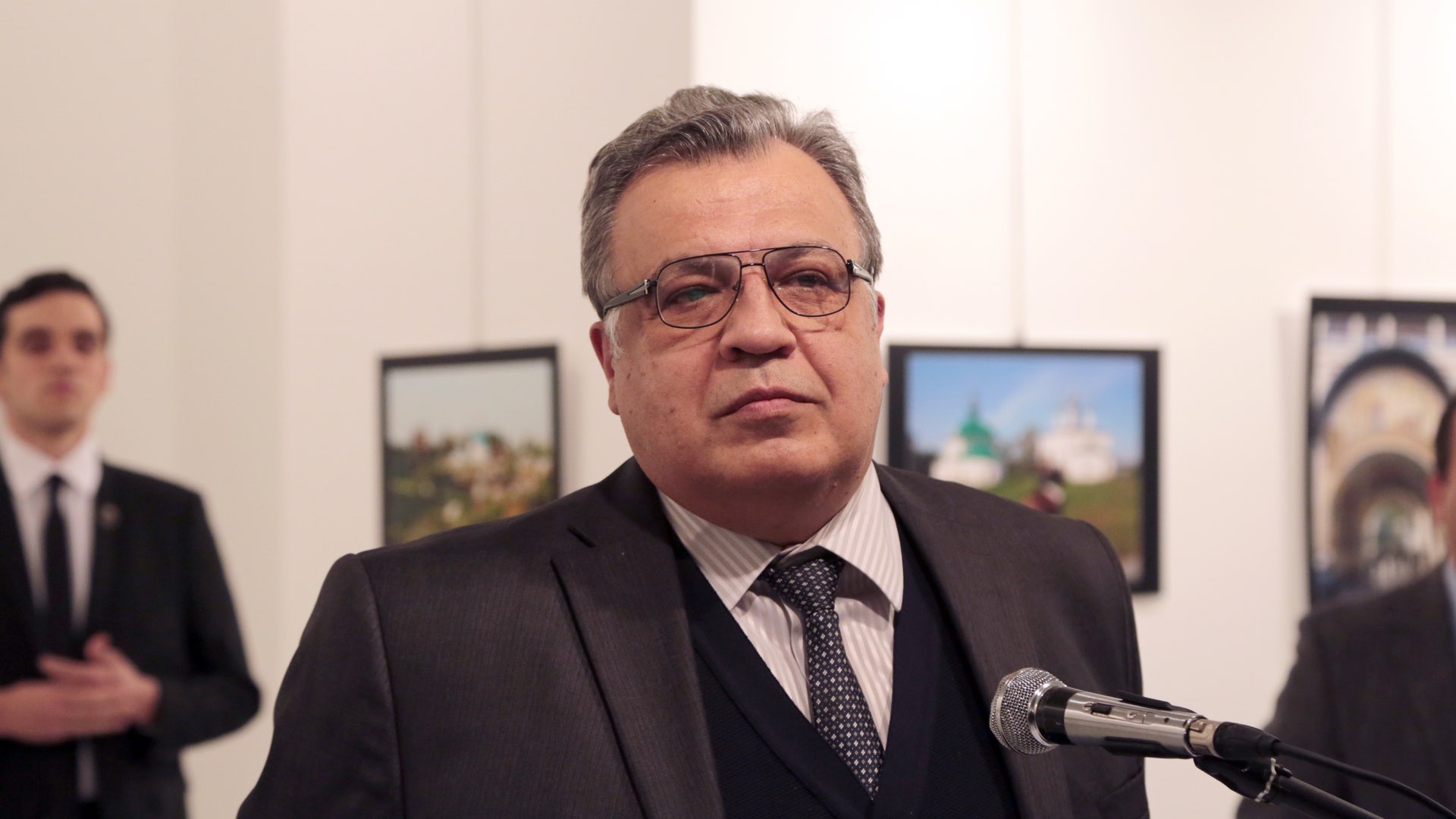 Karlov is shown here speaking at the gallery, as the man who would kill him looms in the background.