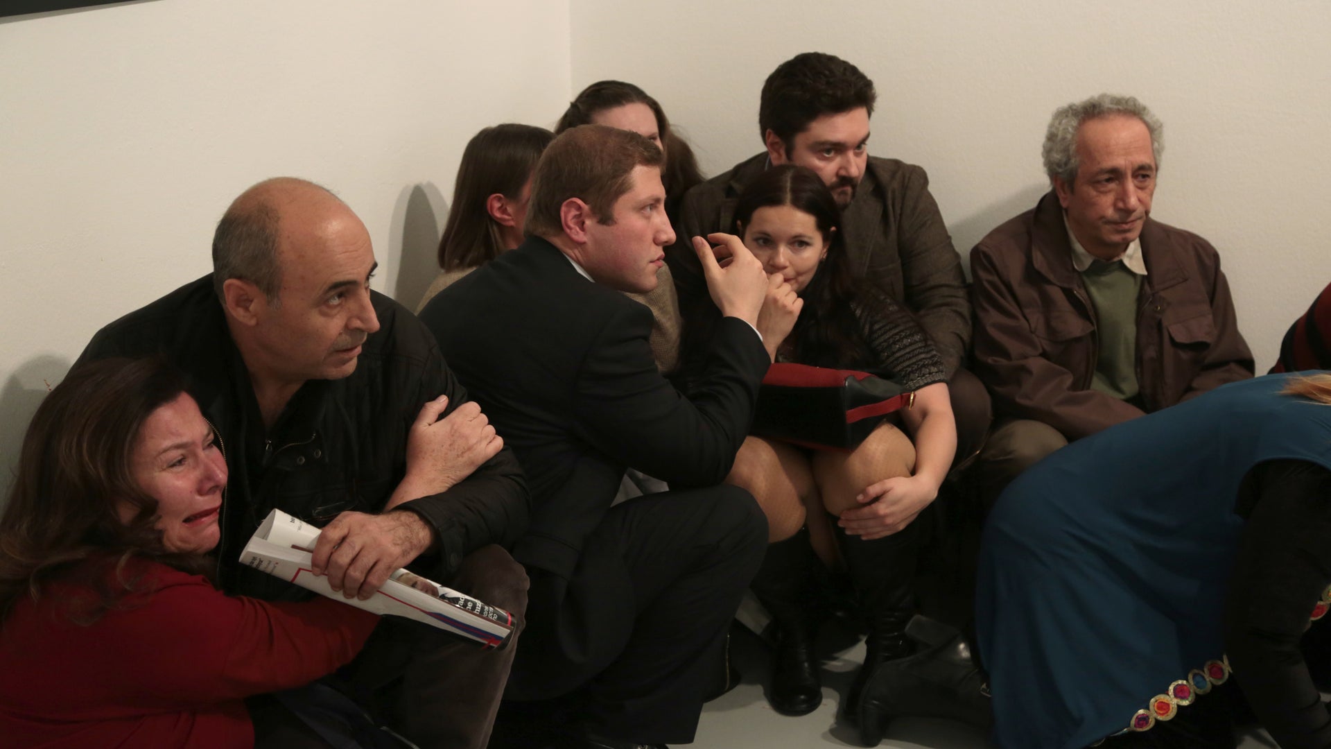 Members of the audience huddle in fear as the gunman waves his weapon around and rants angrily.