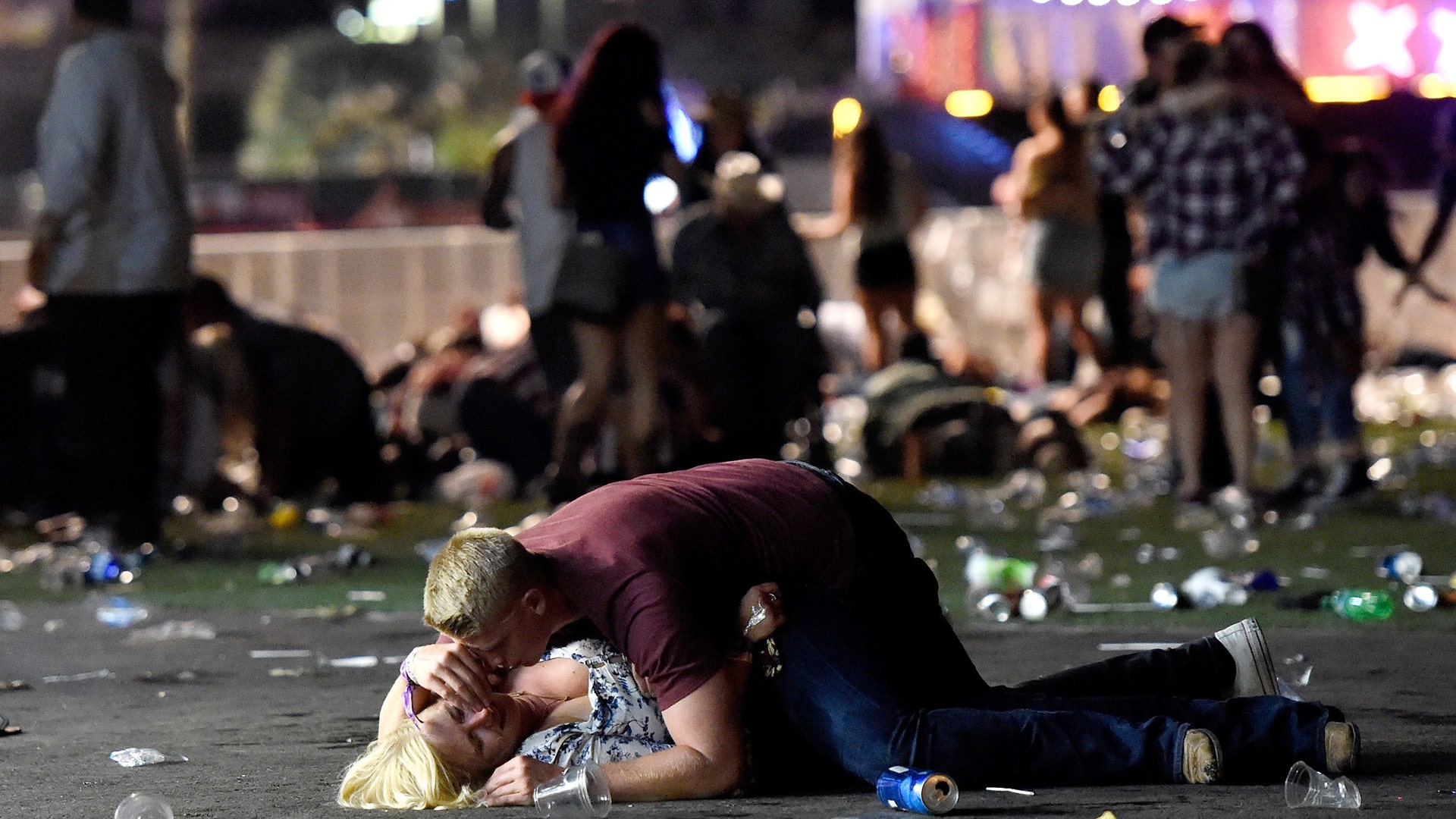 A man lays on top of a woman as others flee the Route 91 Harvest country music festival grounds after a shooting in Las Vegas